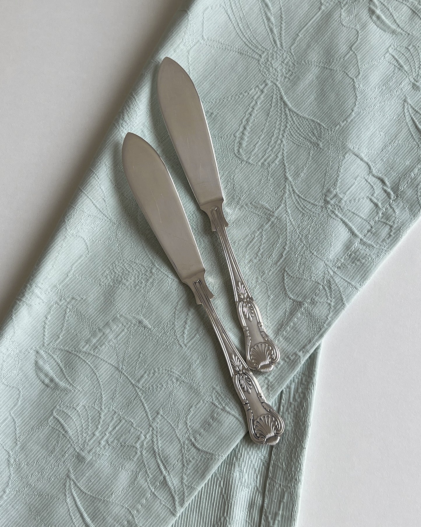 The antique seashell butter knife elegantly poised to serve butter from a platter, highlighting its versatile use for entertaining.