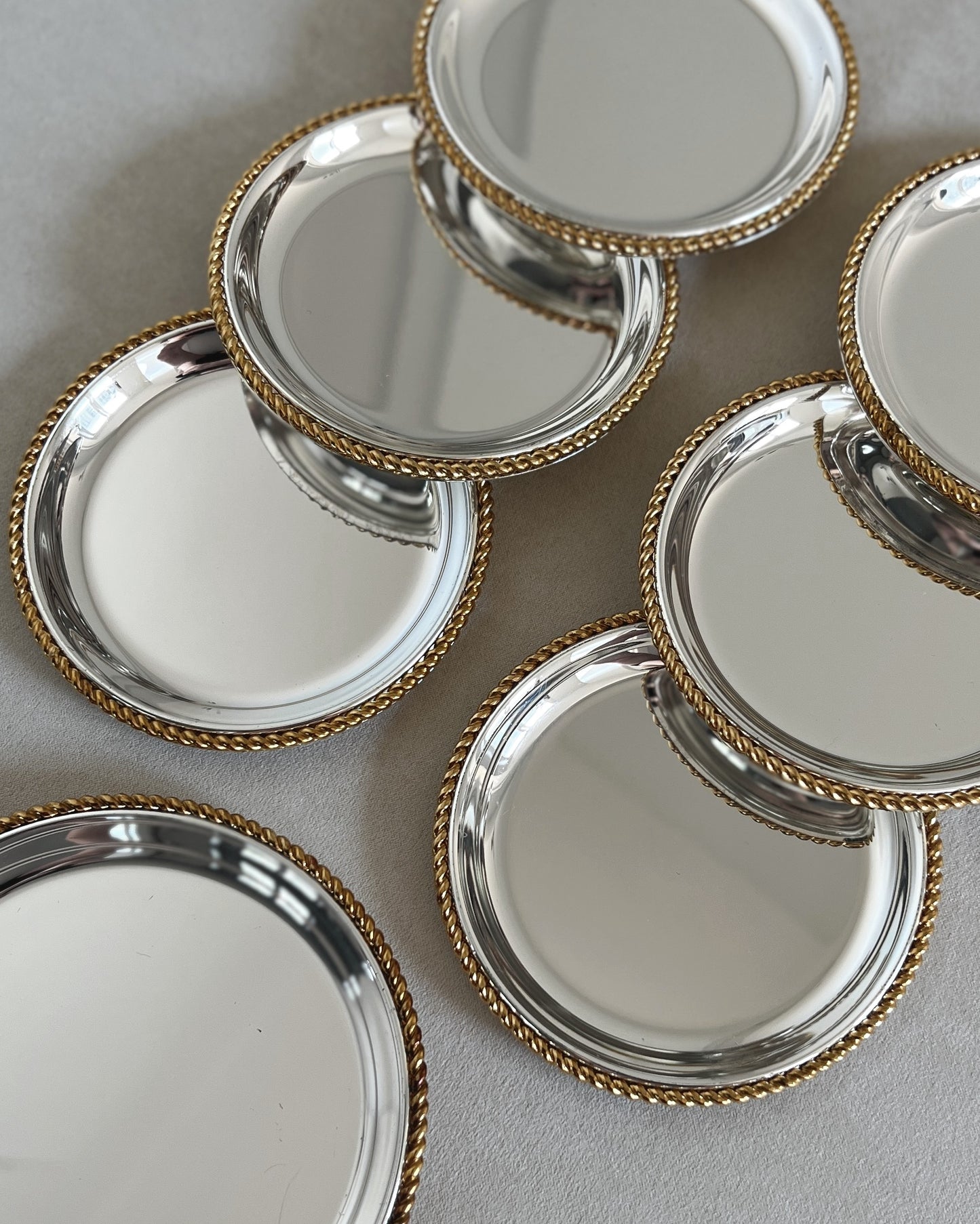 Close-up of the elegant two-tone coasters by BBI Präsent, detailing the contrast between the silver plate and the lustrous gold-plated rim.