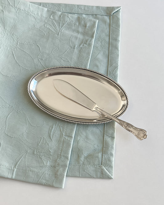 A detailed close-up of the finely modelled seashell motif crowning the handle of the antique English butter knife.