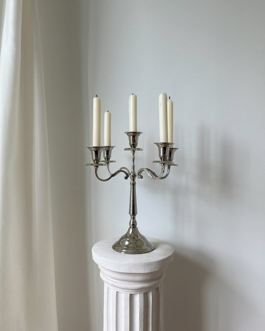 Vintage silver nickel-plated candelabra holding 5 lit tapered candles, illuminating a dining table with refined symmetry.