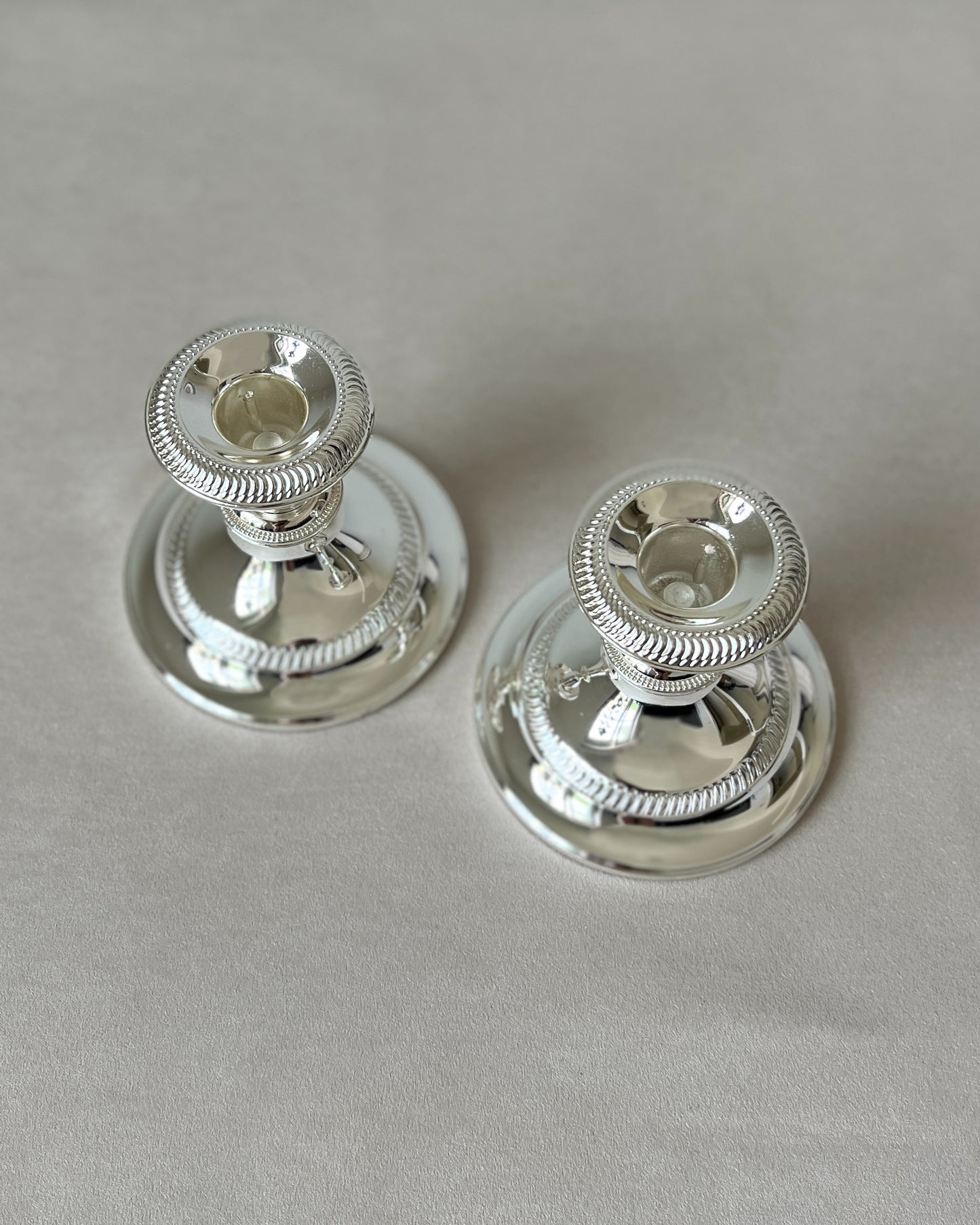 The pair of mid-century silver-plated candlesticks on a dining table or mantelpiece.