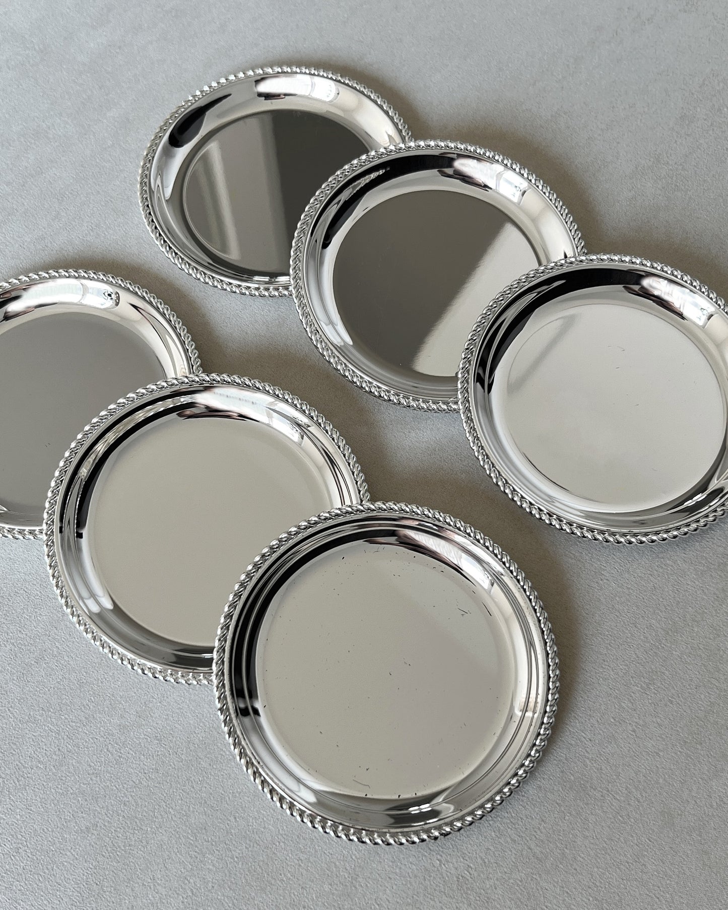 Zoomed-in shot of the 1970s BBI Präsent silver-plated coasters, highlighting the clean lines and sophisticated details of the twisted rope design.