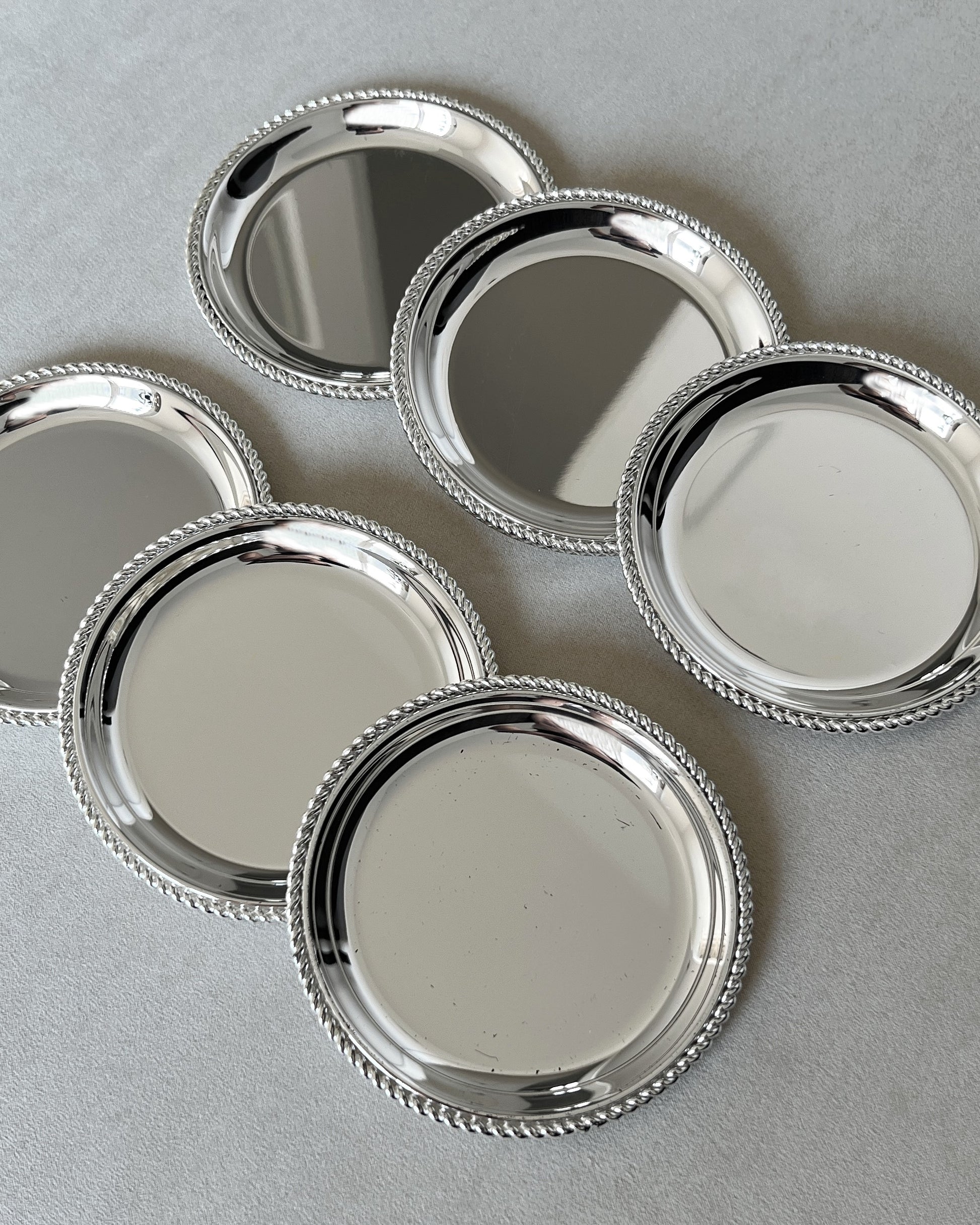 Zoomed-in shot of the 1970s BBI Präsent silver-plated coasters, highlighting the clean lines and sophisticated details of the twisted rope design.