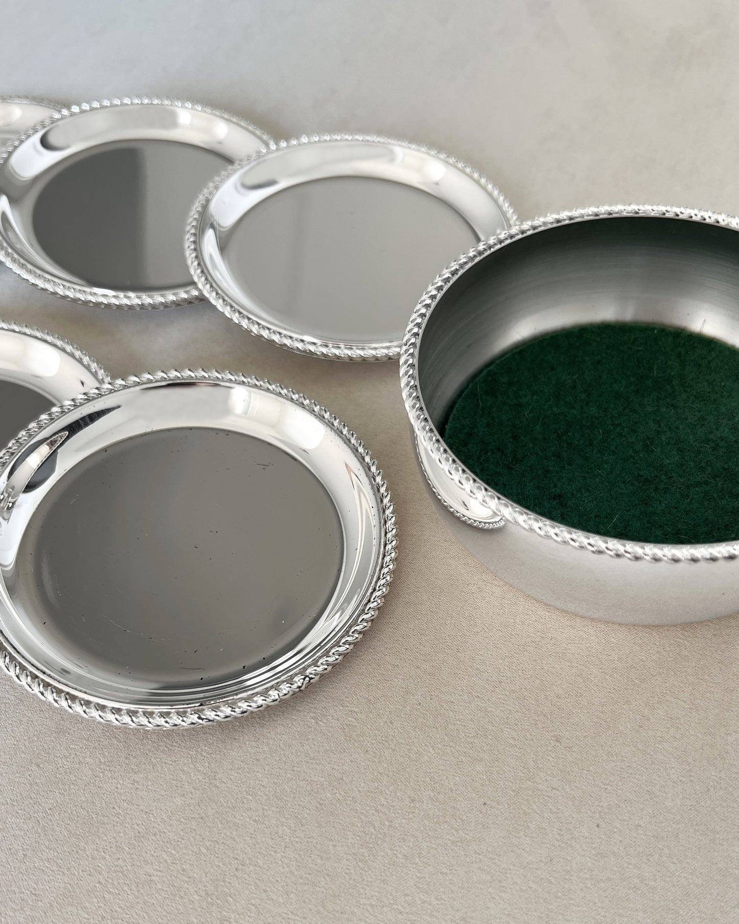A close-up view of the German-made BBI Prasent coasters, showing the superior craftsmanship of the lustrous silver-plating and twisted rope edge detail.