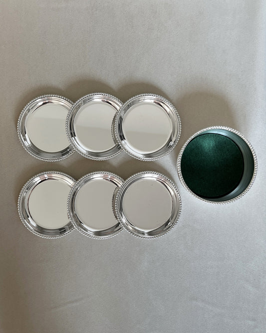 Full set of vintage BBI Präsent silver-plated barware, including six drink coasters and one tall wine bottle coaster with a detailed twisted rope rim.