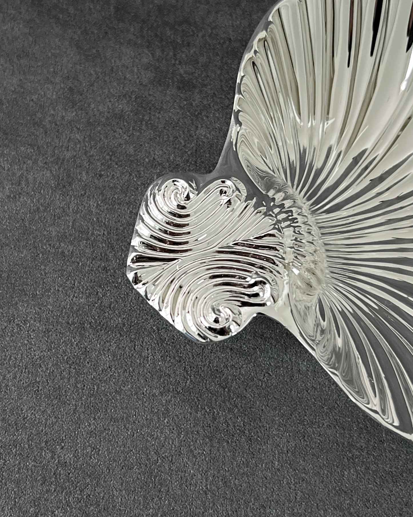 Silver scallop shell dish used as jewelry tray with rings and necklaces, showing versatile decorative function.