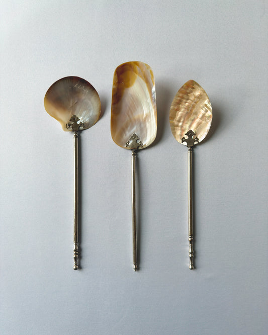A complete 3-piece antique serving set featuring a large spoon, cake server, and pastry server with iridescent mother-of-pearl tops and silver-tone handles.