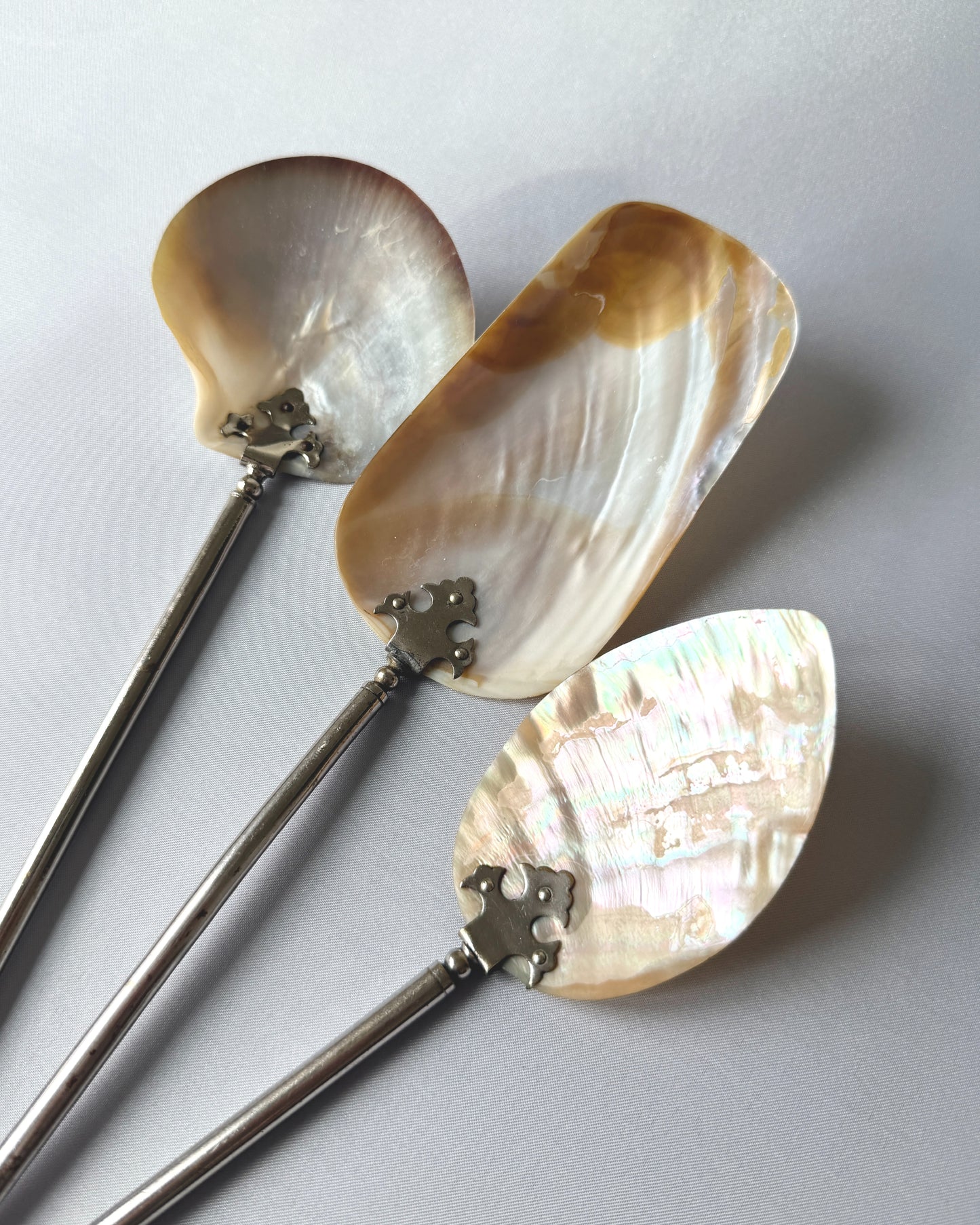 A large antique mother-of-pearl serving spoon, ideal for a refined caviar service or formal tea, displaying its unique hand-carved shell bowl.