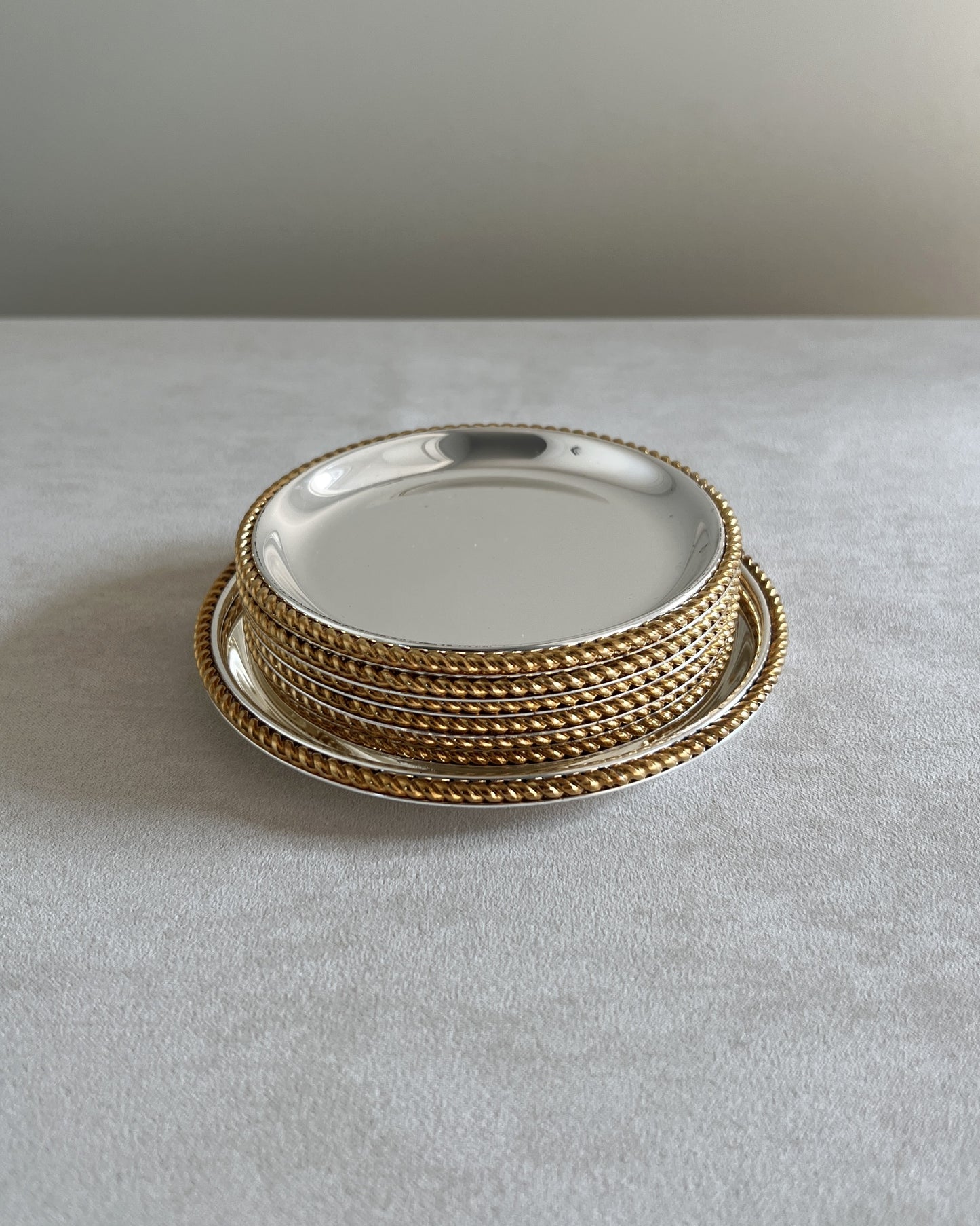 Six drink coasters with gold-plated rims stacked inside the matching flat wine bottle coaster, displaying the luxurious BBI Präsent design.