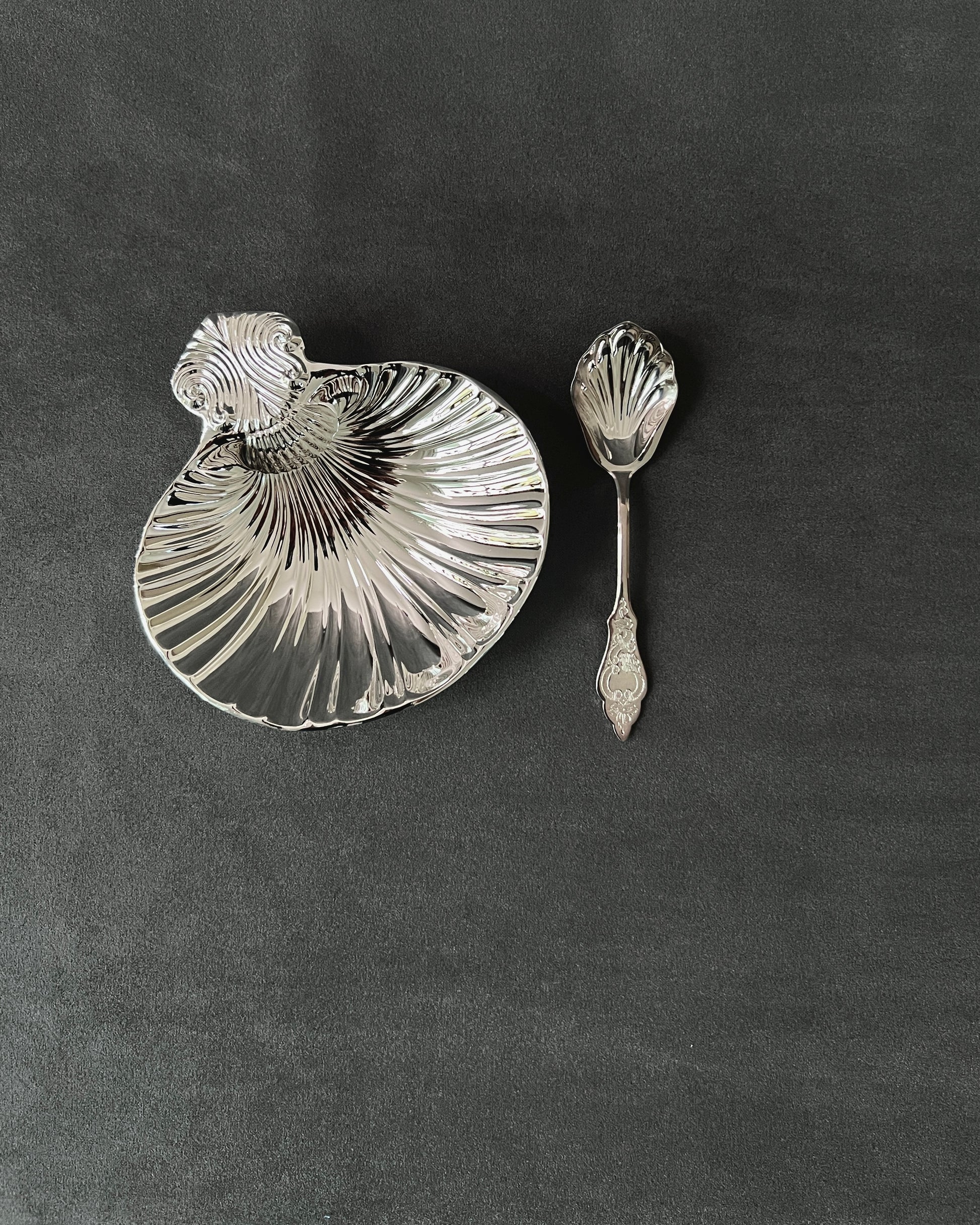 Back view of silver-plated shell dish, revealing smooth underside and stamped maker’s mark on metal base.