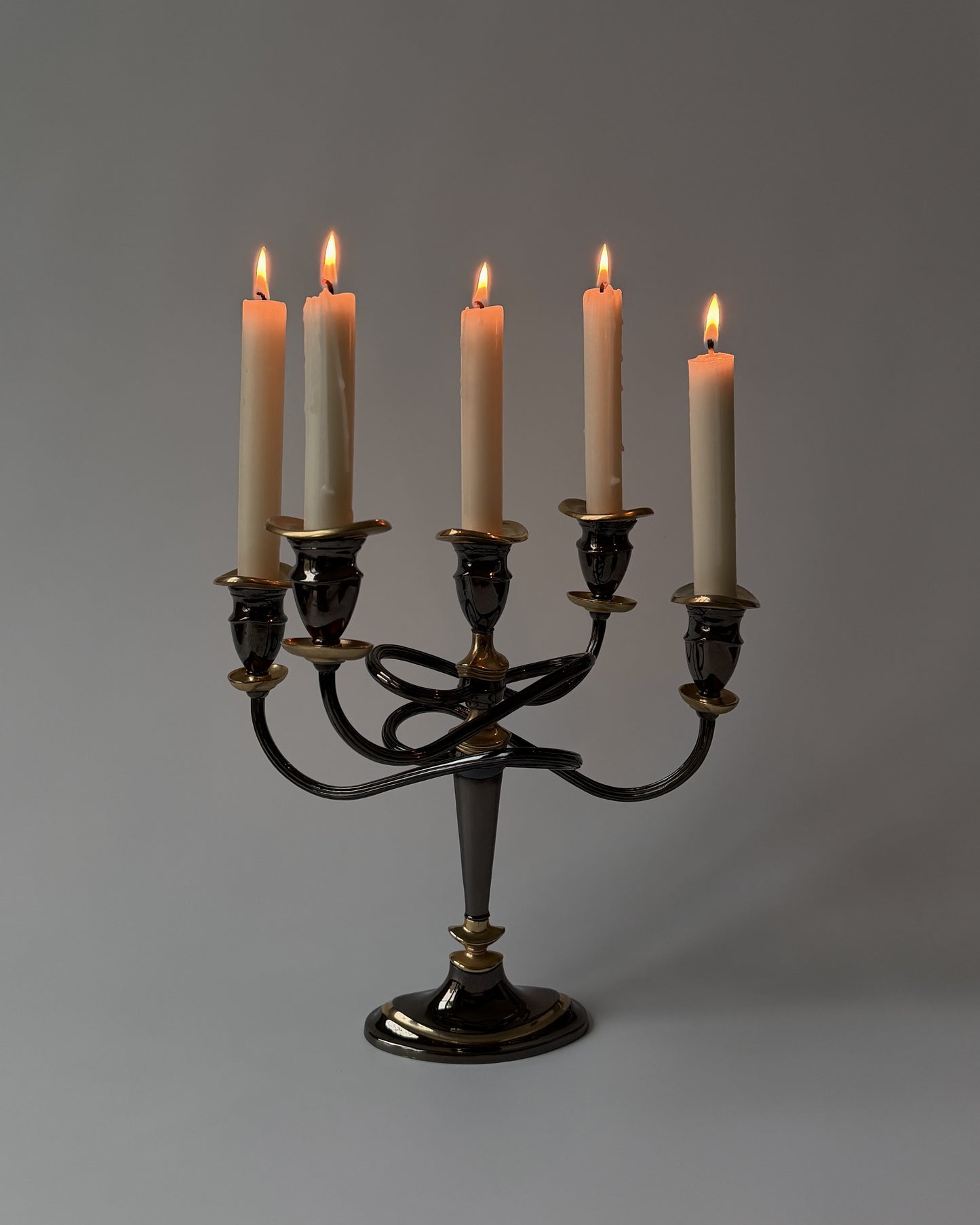 An angled view of the lit candelabra, emphasizing its bold architectural silhouette and unique sculptural form from the late mid-century era.
