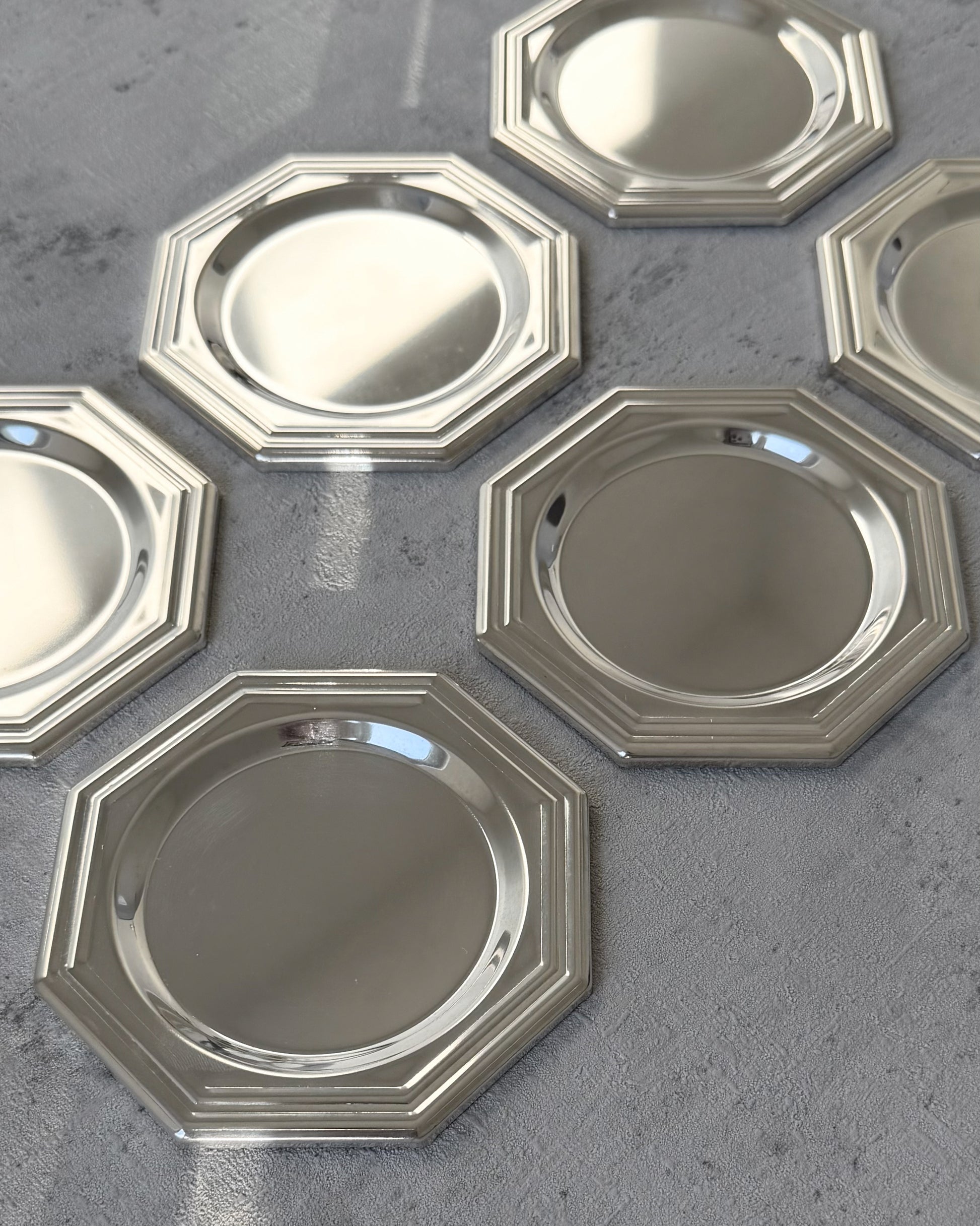 A detailed view of the eight-sided octagonal geometry and sharp architectural lines of a single vintage 1980s silver-plated coaster.