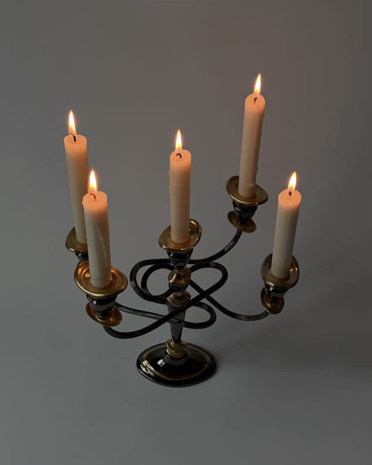 A detailed close-up of the burning candles on the twisted metal arms, highlighting the atmospheric contrast of the dark bronze-toned finish.