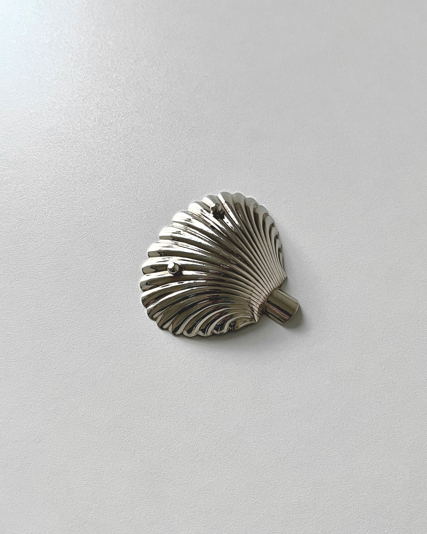 The compact Florentine 800 silver shell ashtray held in a hand to demonstrate its pocket-sized scale, perfect for travel or as a small decorative dish.