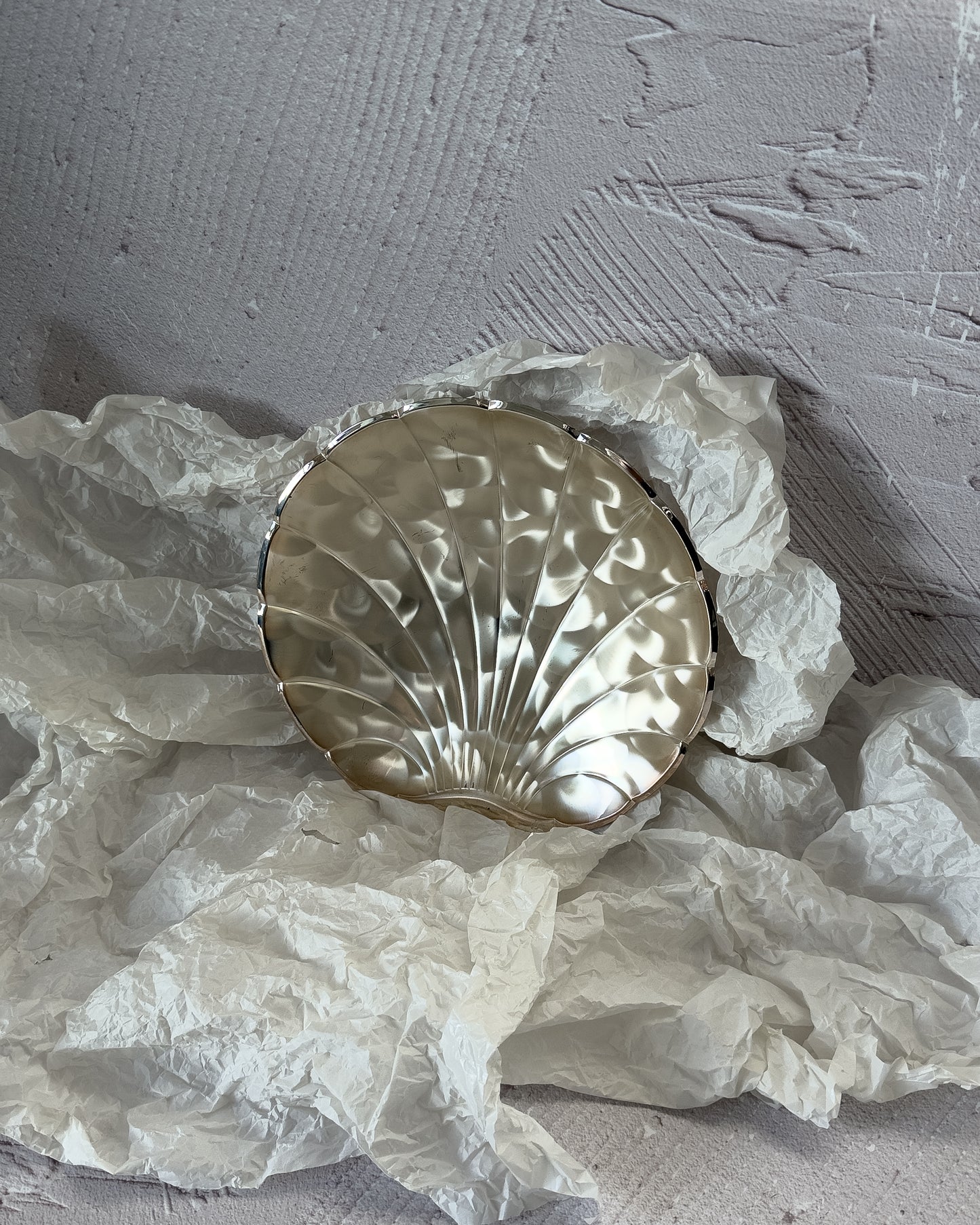 An angled view of the large silver-plated ikora shell, demonstrating its size and depth as a grand fruit bowl or dining table centerpiece.