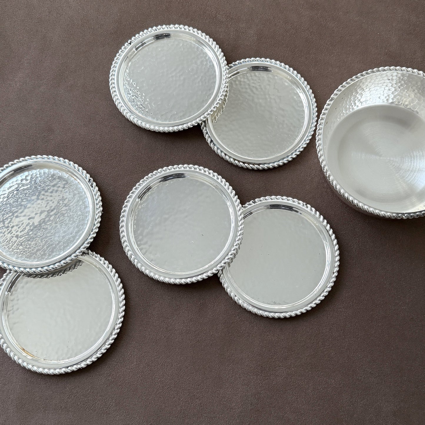 A luxury display of the rare hammered silver coaster set, capturing the stunning play of light and reflection on the silver-plated surfaces.