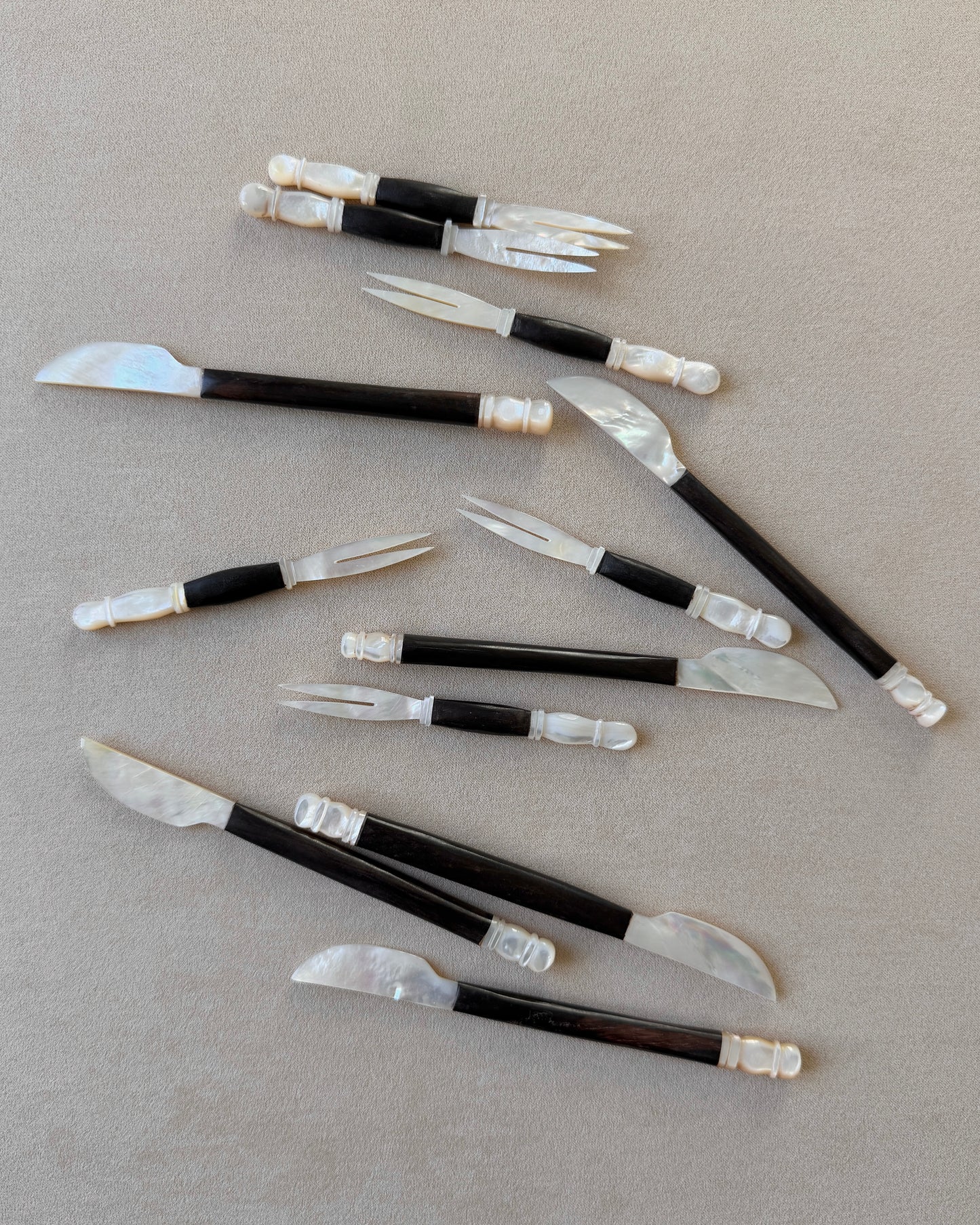An angled perspective of the teak and mother-of-pearl knife, demonstrating its versatility as a luxury pâté spreader or centerpiece for a high-end charcuterie board.