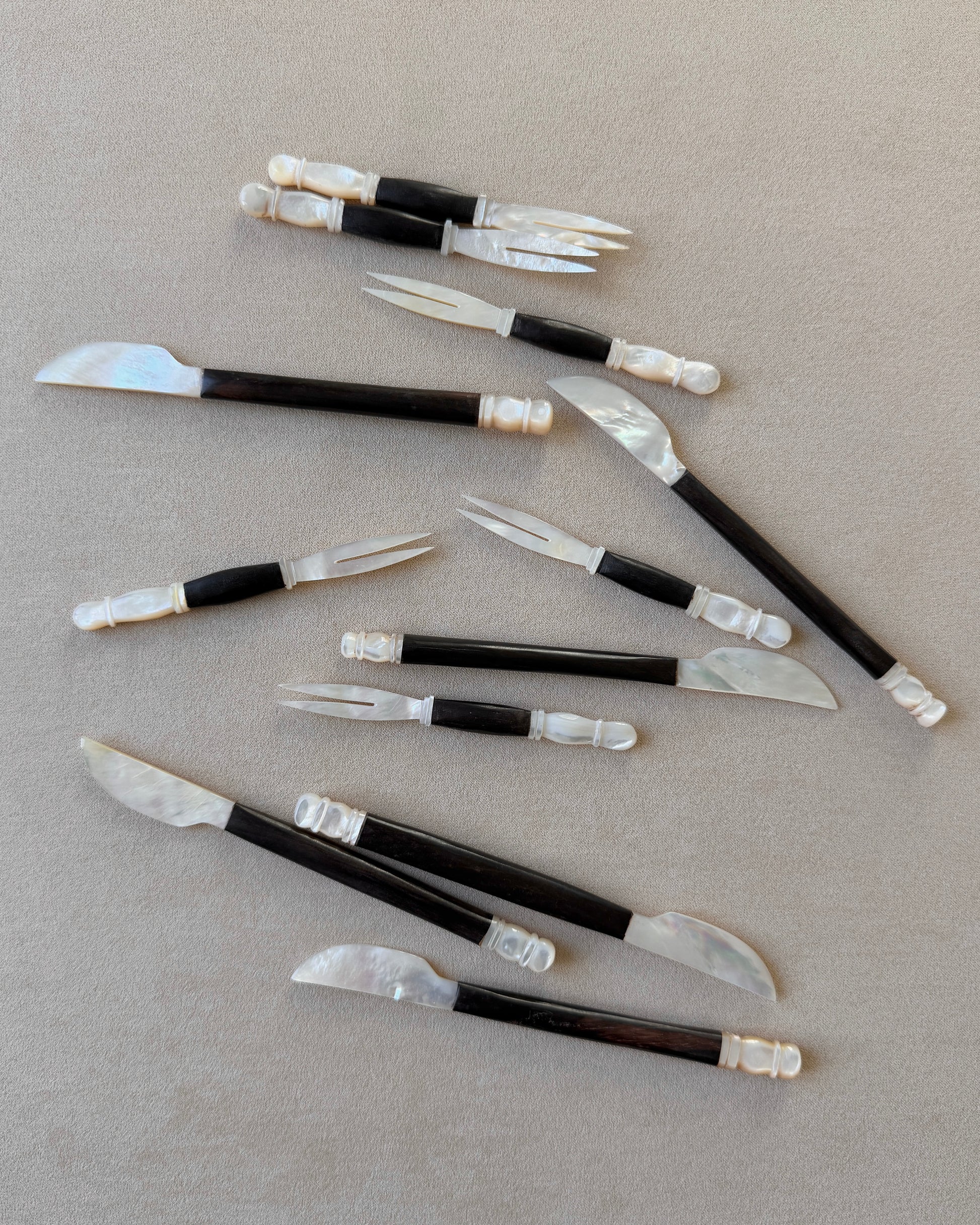 An angled perspective of the teak and mother-of-pearl knife, demonstrating its versatility as a luxury pâté spreader or centerpiece for a high-end charcuterie board.