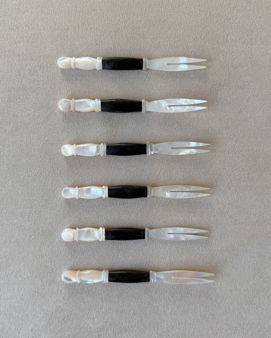 A mid-century modern appetizer fork featuring a hand-carved dark teak wood handle and a luminous mother-of-pearl head, isolated on a neutral background.