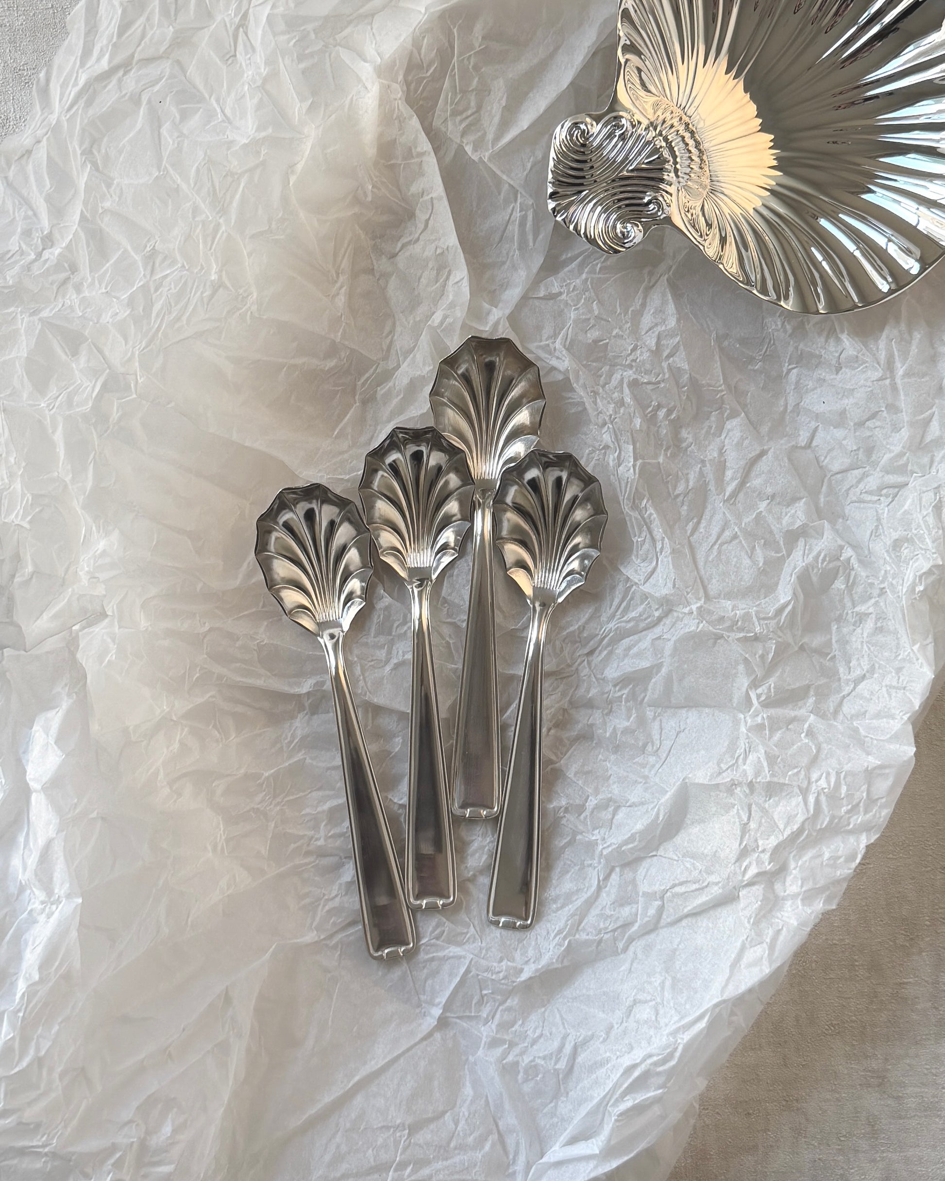 Four German mid-century silver-plated shell spoons arranged with a decorative silver shell on a clean white background.