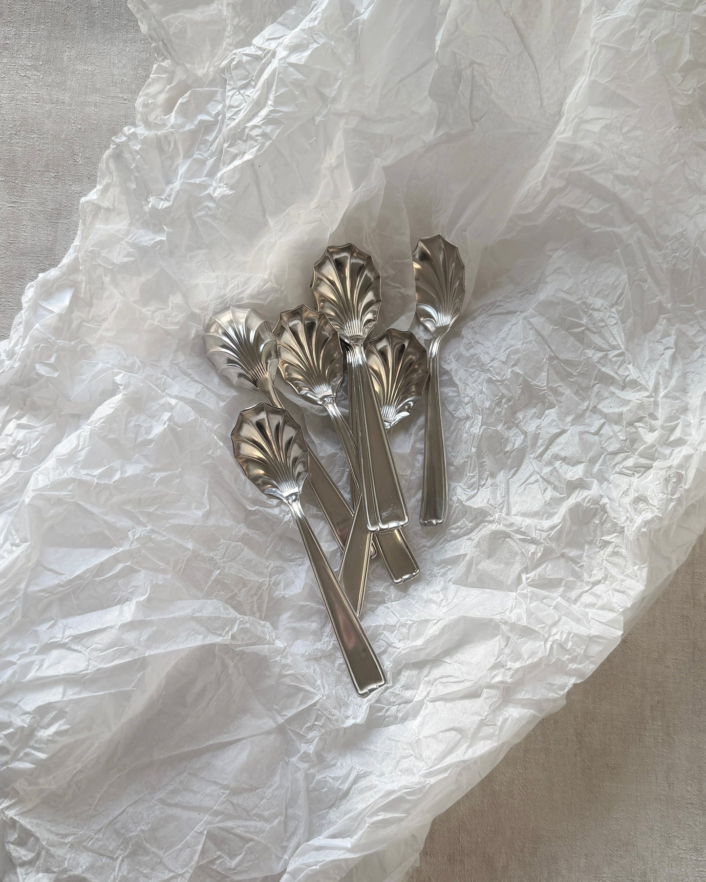 A set of four vintage Michelin silver-plated shell spoons isolated on white, highlighting their fan-shaped bowls and sleek handles.