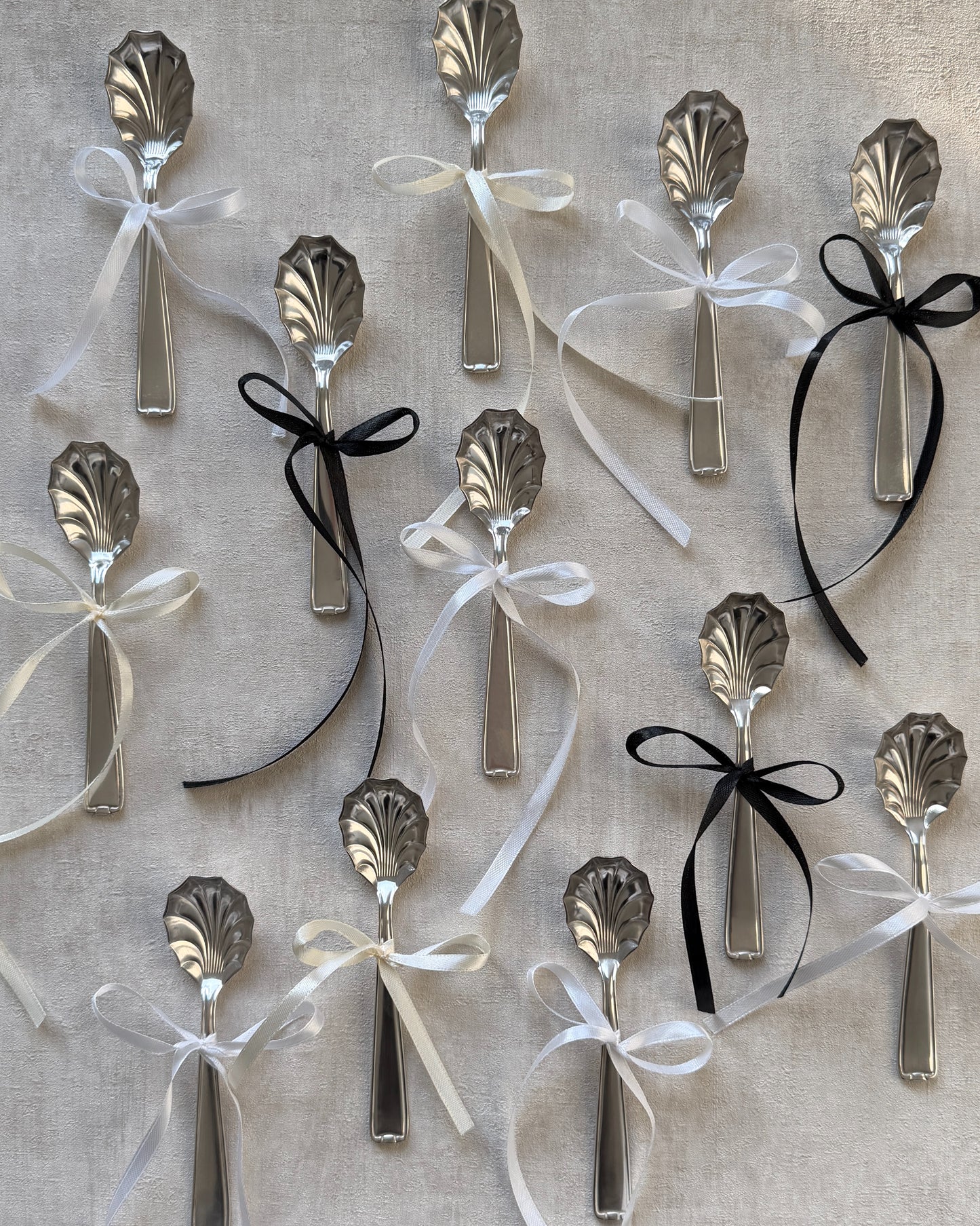 A group of vintage Michelin silver-plated shell serving spoons tied with decorative bows, showcasing them as perfect holiday or host gifts.
