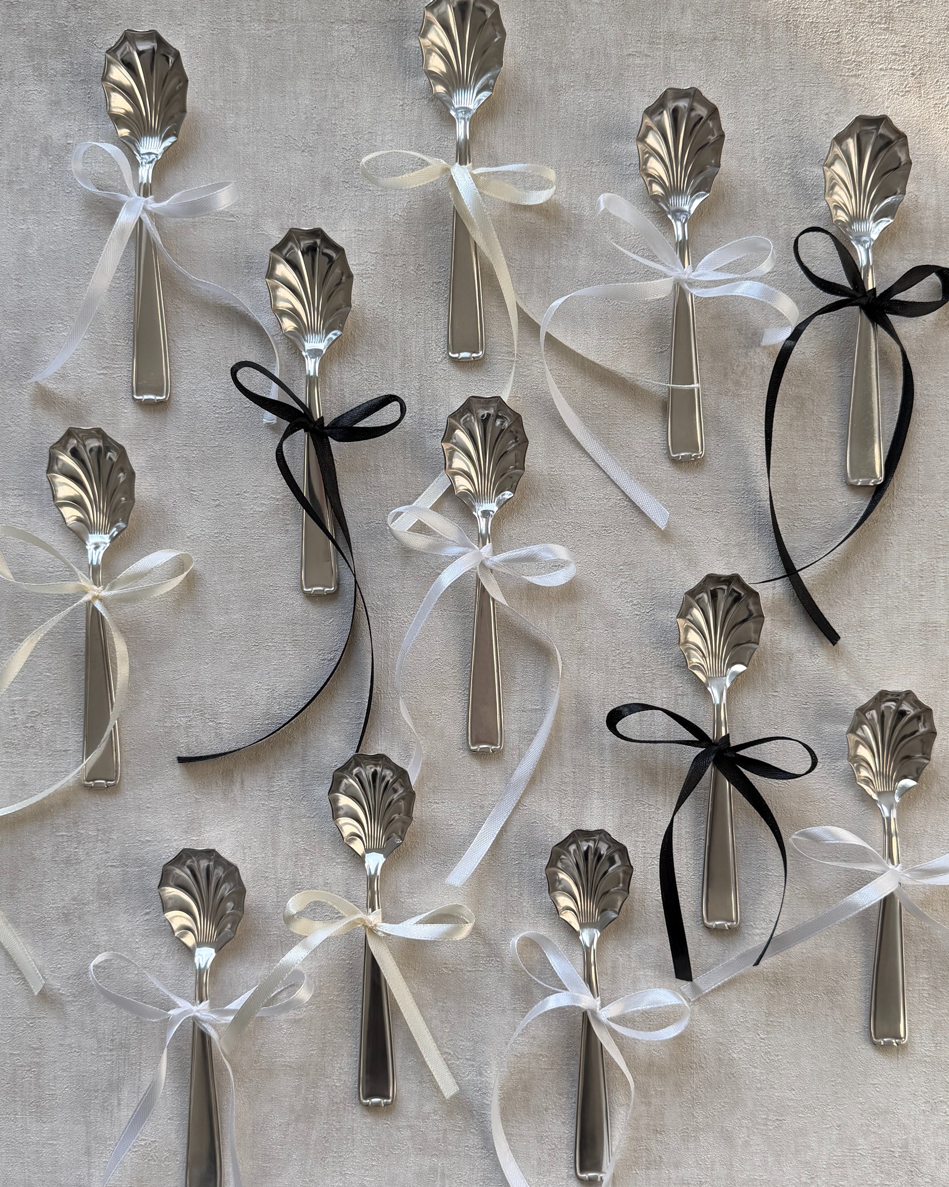 A group of vintage Michelin silver-plated shell serving spoons tied with decorative bows, showcasing them as perfect holiday or host gifts.