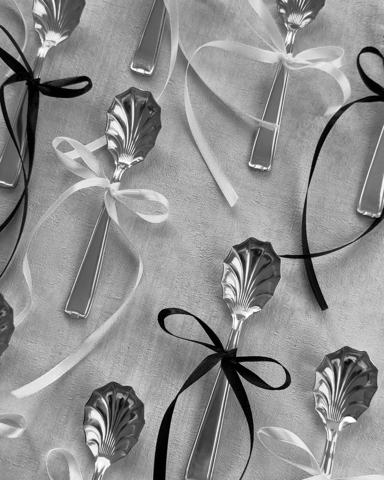 Black and white lifestyle photo of multiple Michelin silver shell spoons adorned with bows, emphasizing their vintage charm and collectible nature.