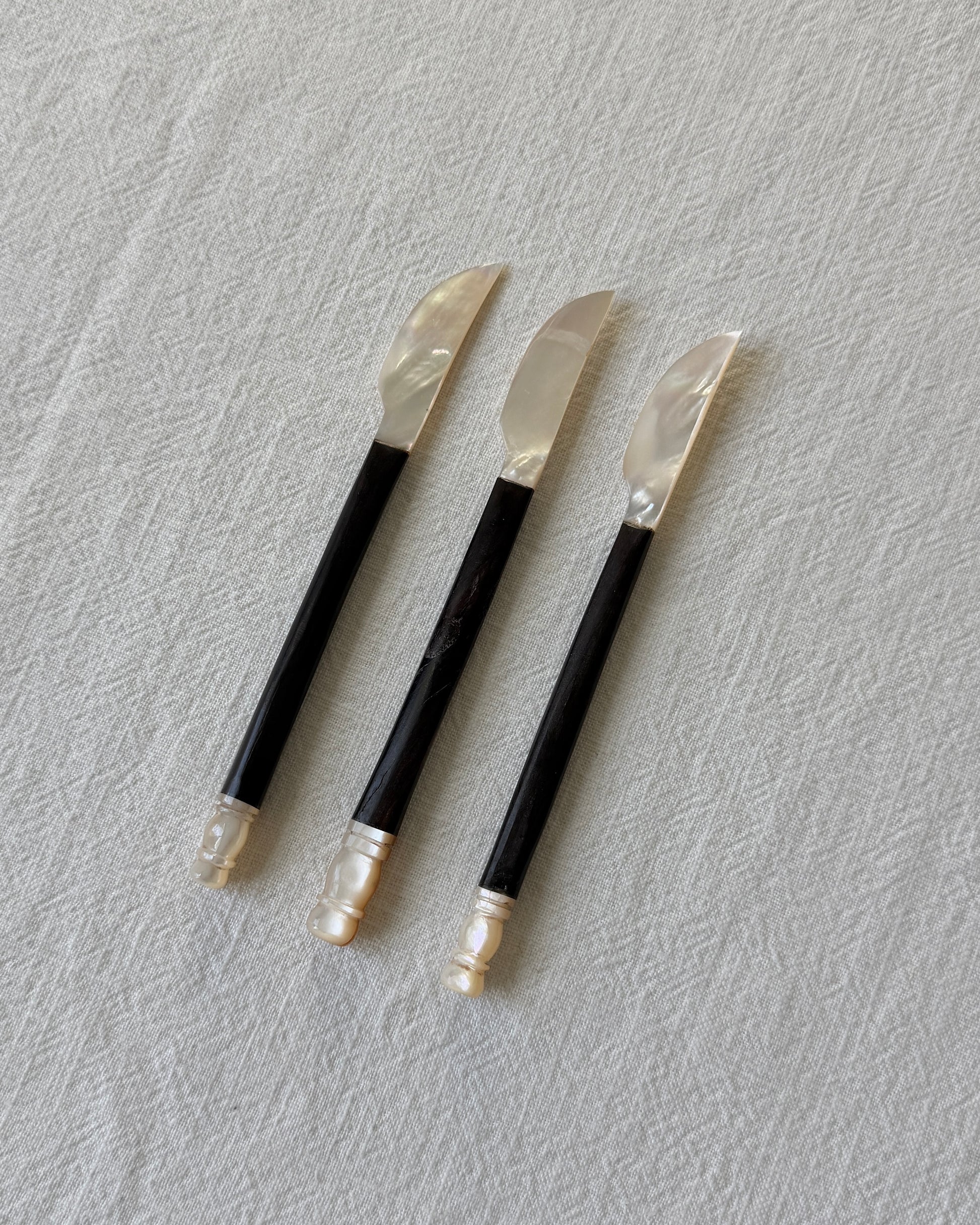 A side profile of the minimalist serving knife, showing the elegant silhouette and the seamless joinery between the natural shell and the teak wood.