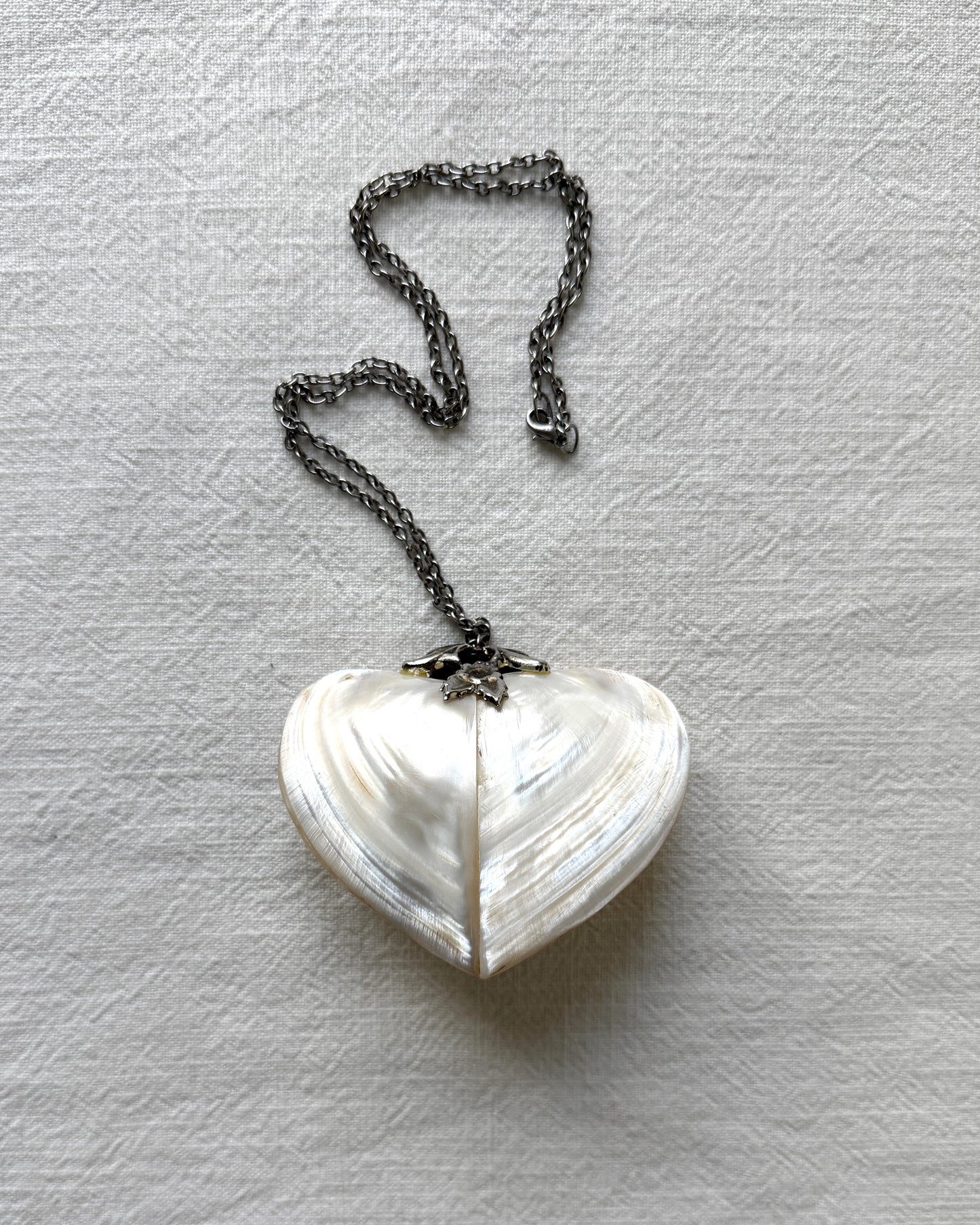 Side profile of the antique heart trinket box pendant, showing the depth of the shell construction and the secure lidded closure mechanism.