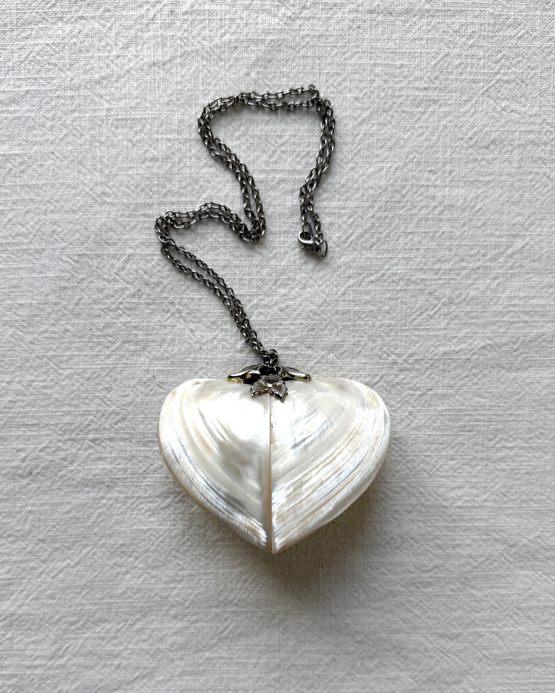 Side profile of the antique heart trinket box pendant, showing the depth of the shell construction and the secure lidded closure mechanism.