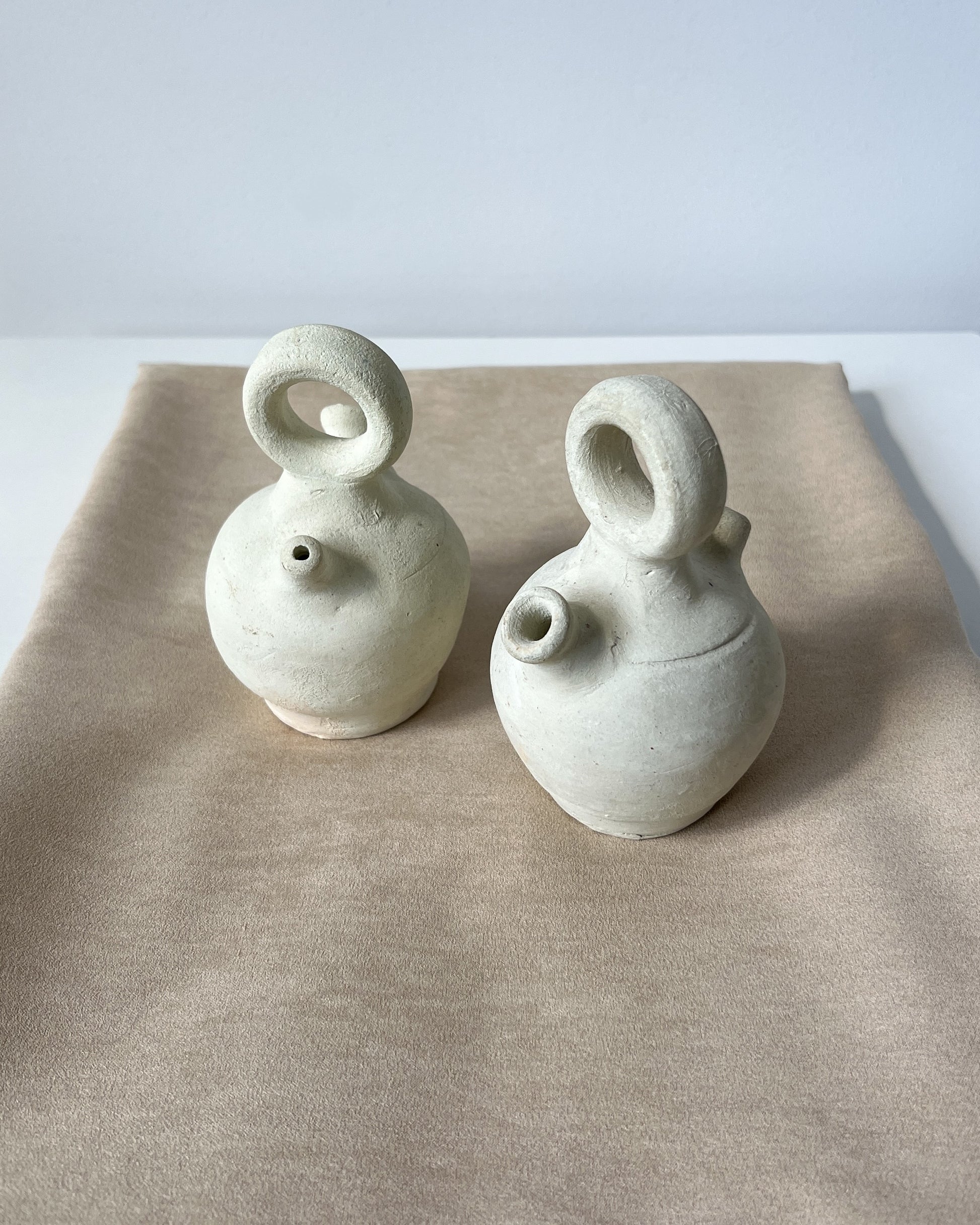 Side profile of a mid-century mini botijo jug crafted in Spain, showing its curved handle, narrow pouring spout, and unglazed porous clay surface, perfectly illustrating the functional elegance of this small 19.5 cm Búcaro water pitcher for tabletop decor.
