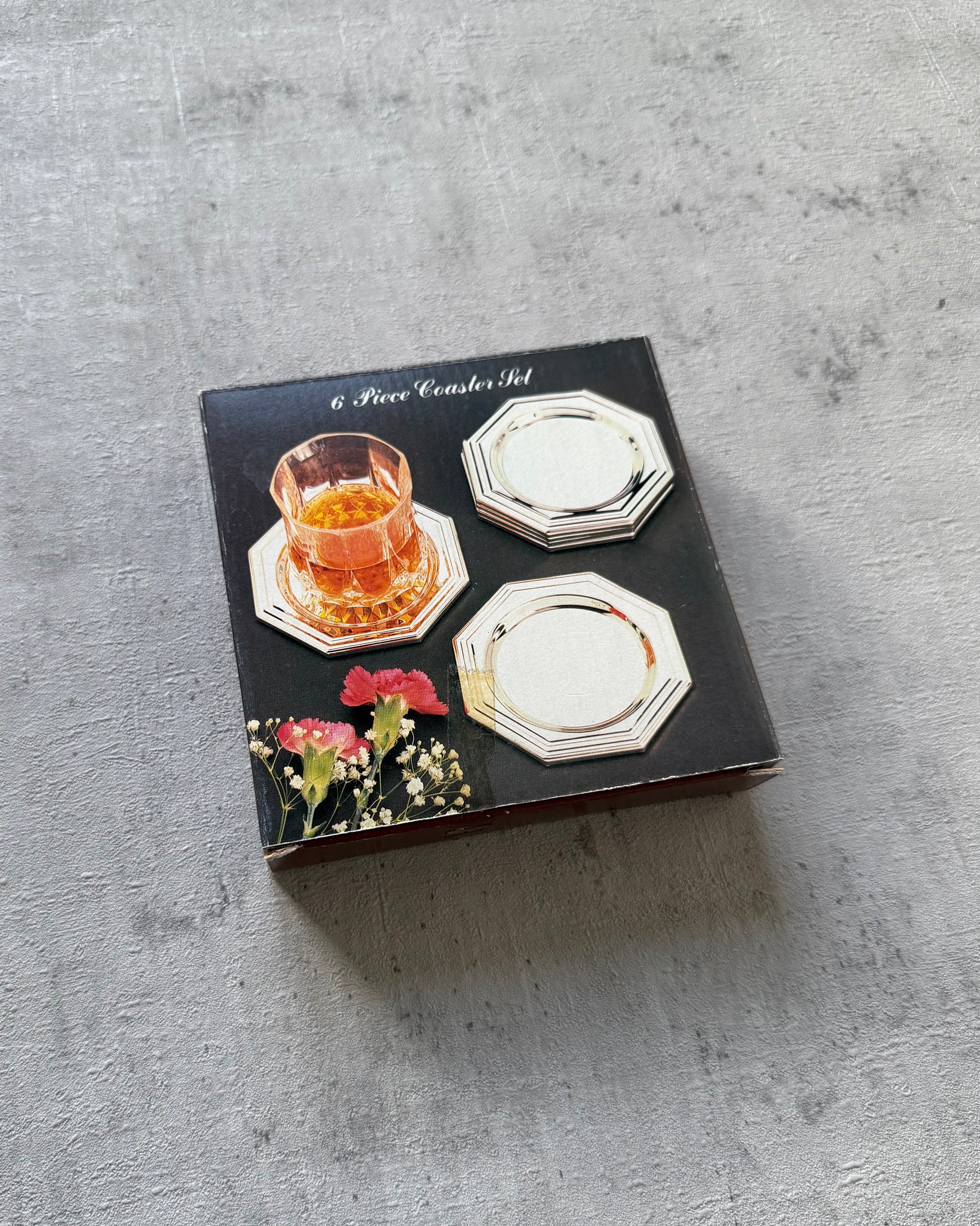 The set of six octagonal silver coasters preserved in their original vintage 1980s packaging, confirming their rare, unused New Old Stock condition.