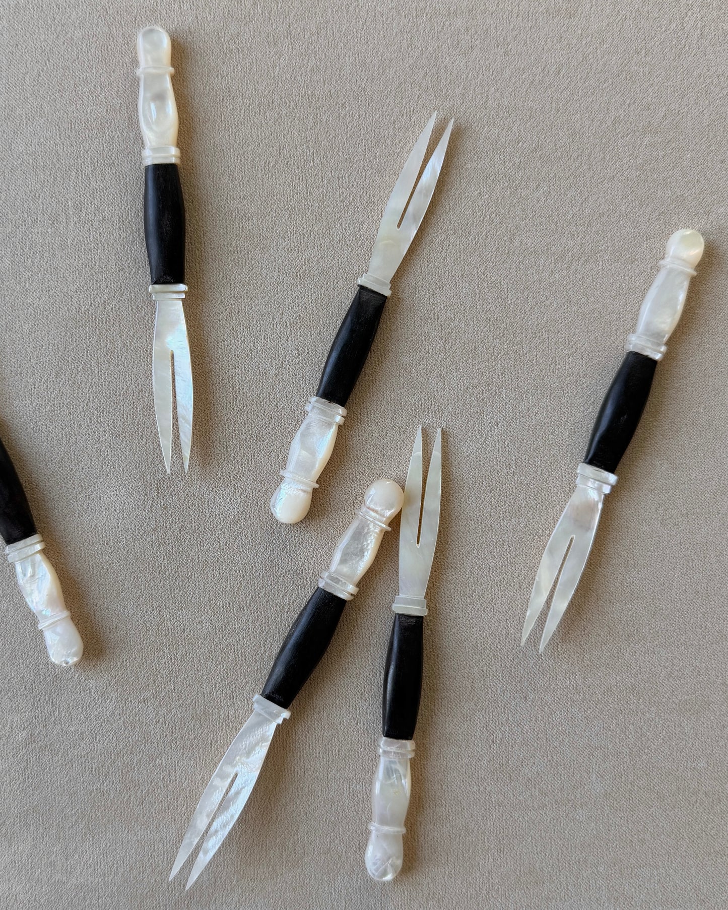 Detail of the iridescent mother-of-pearl fork head, emphasizing its non-reactive surface which is ideal for serving acidic appetizers like olives and pickles.