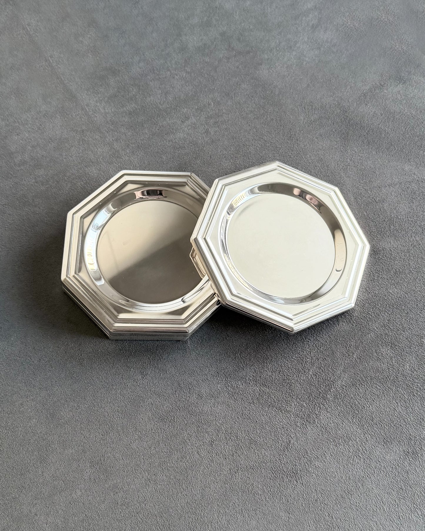 The highly reflective mirror-like surface of an 1980s minimalist coaster, highlighting the pristine silver plating that captures and reflects light.