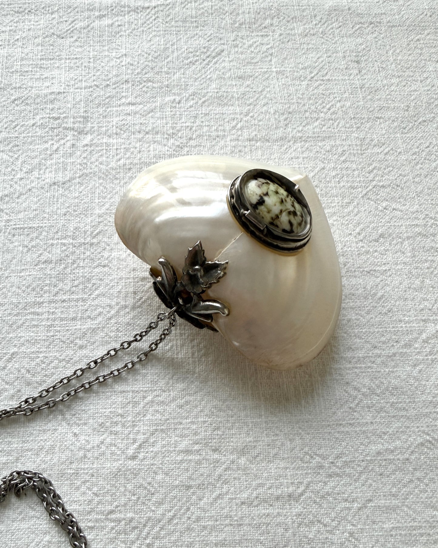 A luminous mother-of-pearl heart necklace isolated on white, capturing the soft glow of the shell, perfect as a romantic Valentine's Day or anniversary gift.