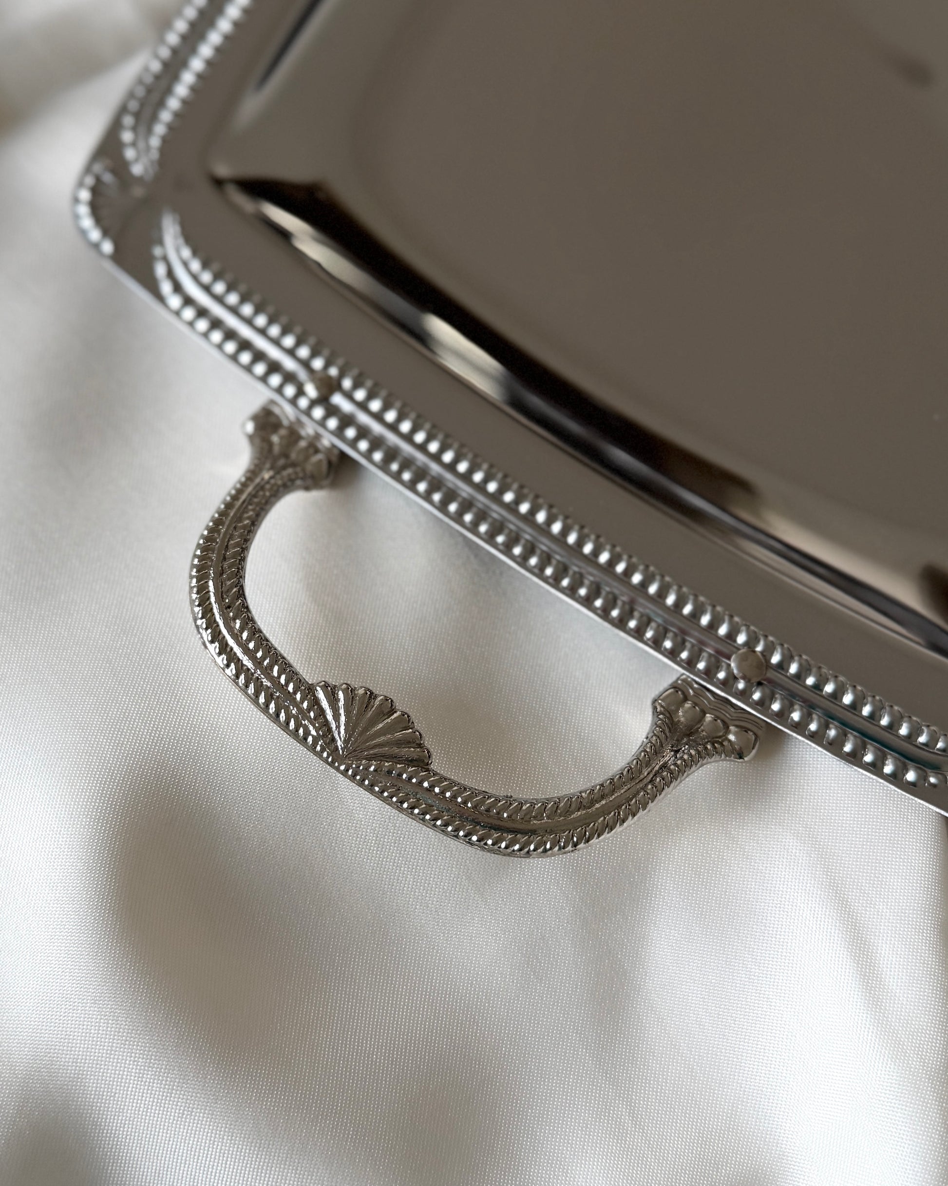 A detailed close-up of the coquille or scallop shell motif handle, showcasing the intricate Neoclassical design and the brilliant luster of the silver plate.
