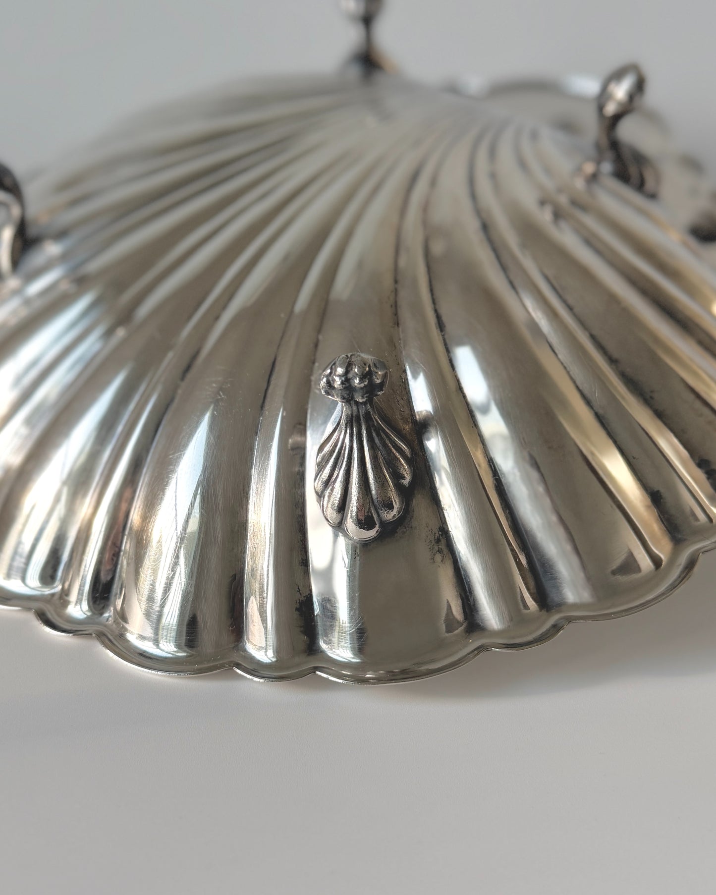 Close-up detail of the ridged scallop shell texture and brilliant mirror-like silver-plated finish of the Sheffield maritime serving dish.