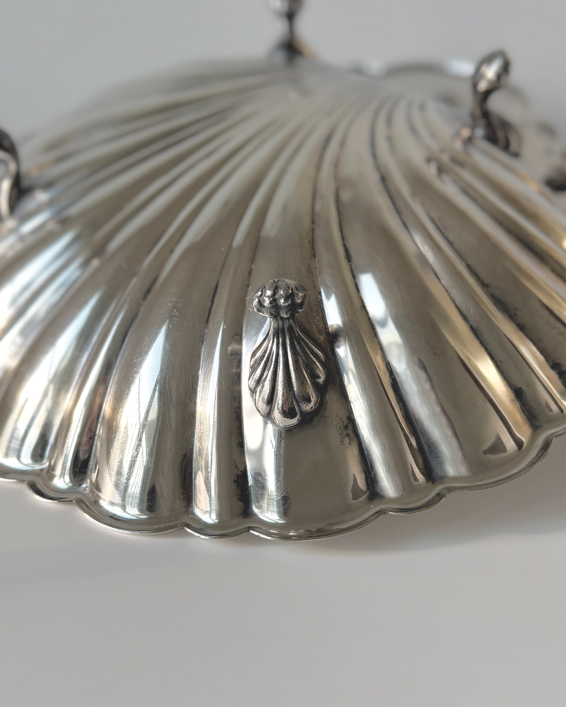 Close-up detail of the ridged scallop shell texture and brilliant mirror-like silver-plated finish of the Sheffield maritime serving dish.
