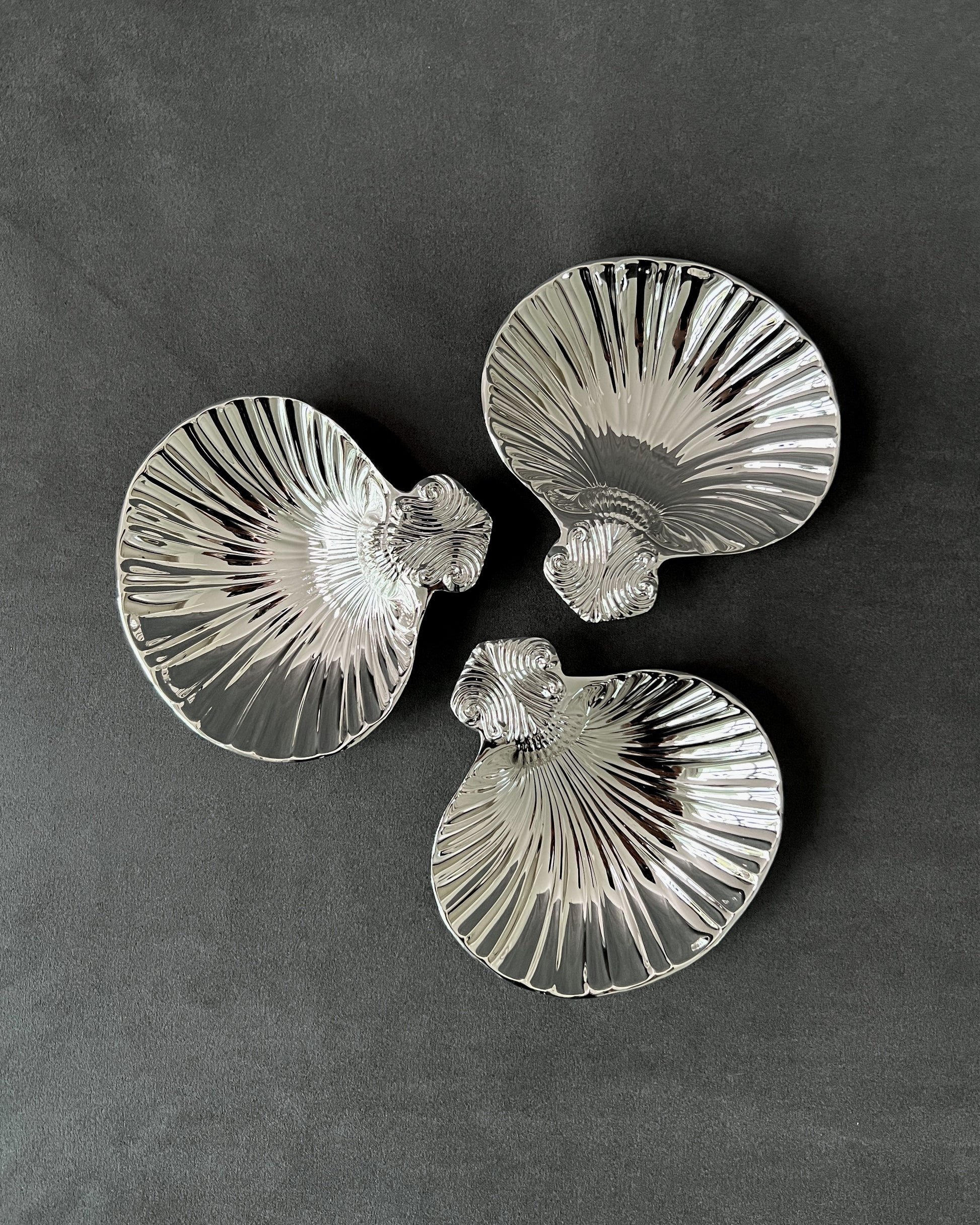 Lovely vintage silver-plated scallop shell dish on a gray background, showcasing mid-century ridged design and reflective metal finish.