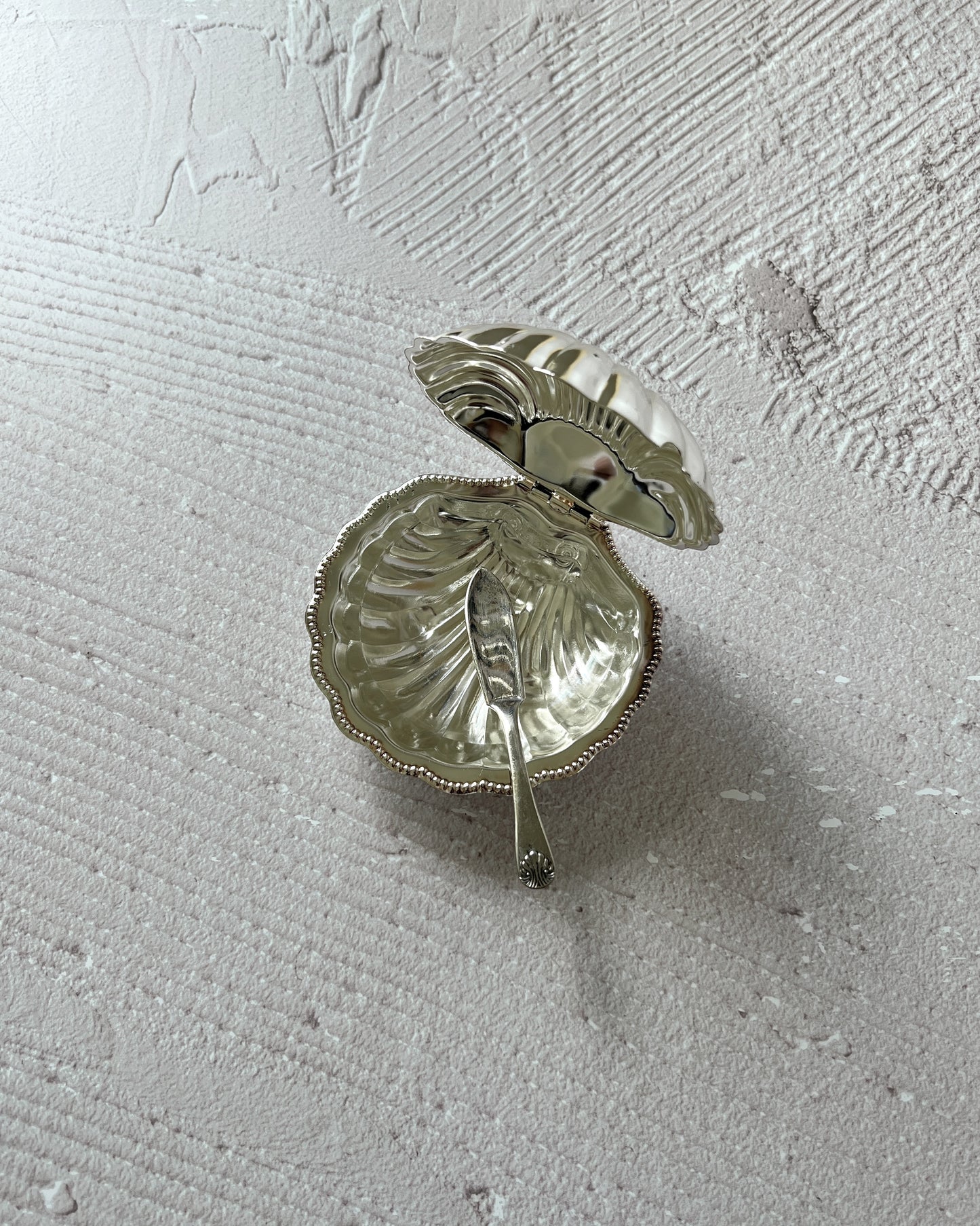 Close-up of the vintage silver-plated shell serving dish by Sheffield, featuring the pristine, removable glass insert ideal for butter or caviar.