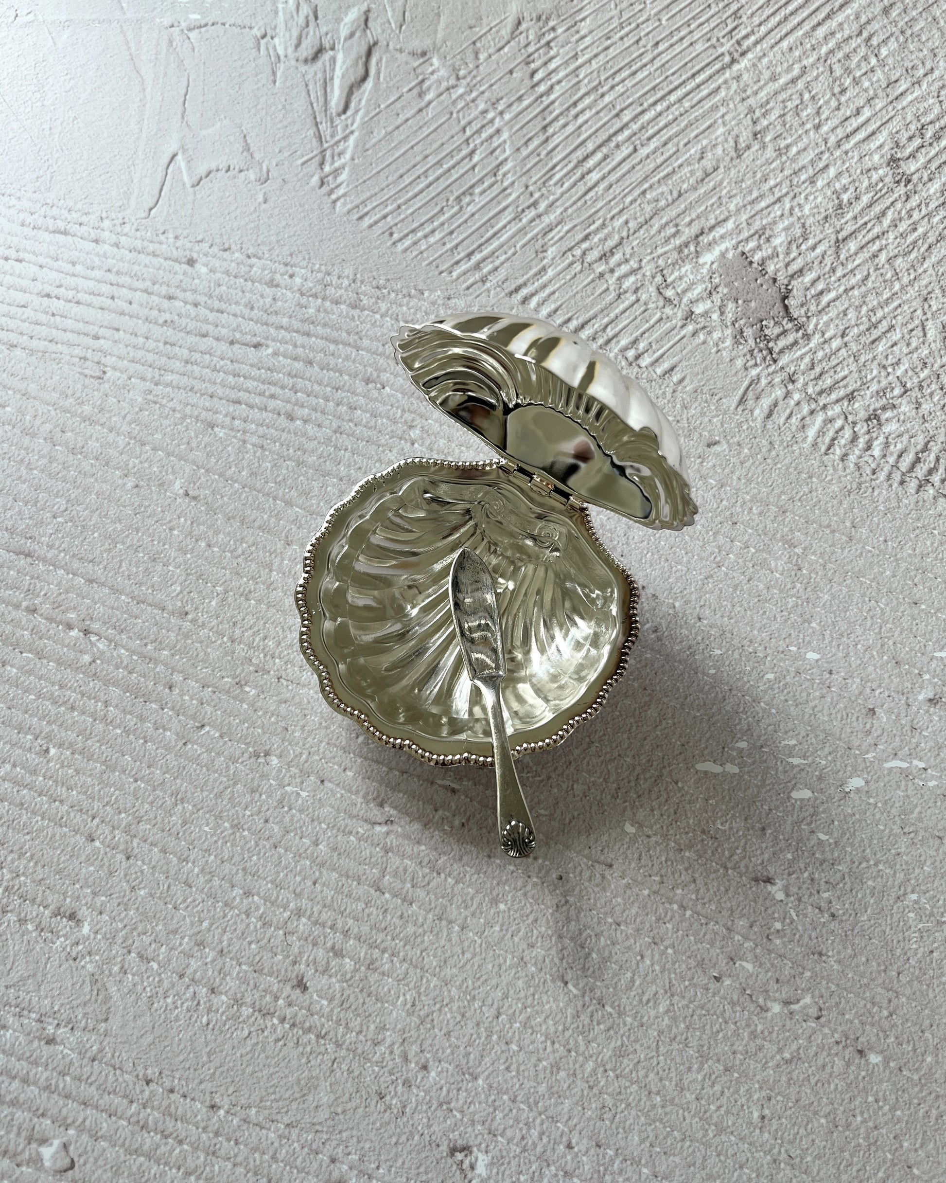 Close-up of the vintage silver-plated shell serving dish by Sheffield, featuring the pristine, removable glass insert ideal for butter or caviar.