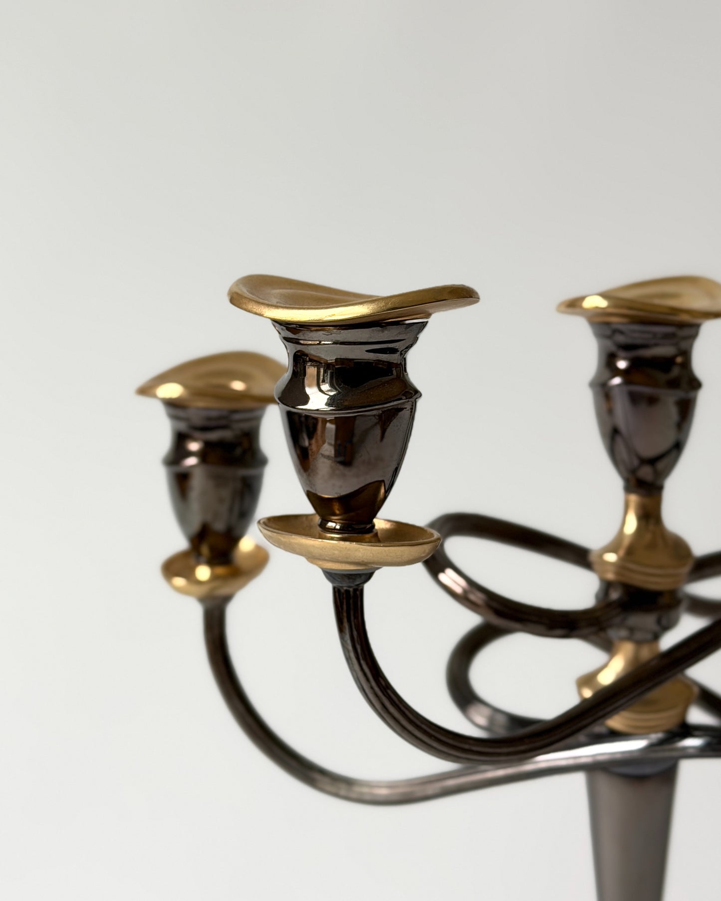 Macro shot of the twisted metal arm, showcasing the high-quality craftsmanship and the sophisticated gold-plated detailing against the dark metal.