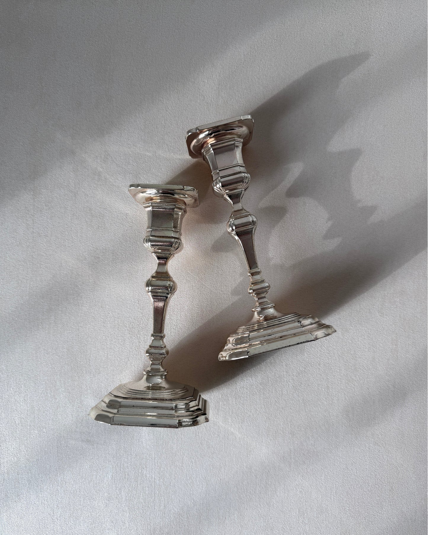 An angled perspective of the two BMF silver-plated candlesticks, showing their clean architectural lines and stability for a dining table centerpiece.