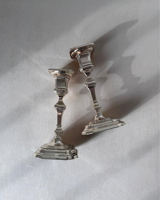 An angled perspective of the two BMF silver-plated candlesticks, showing their clean architectural lines and stability for a dining table centerpiece.