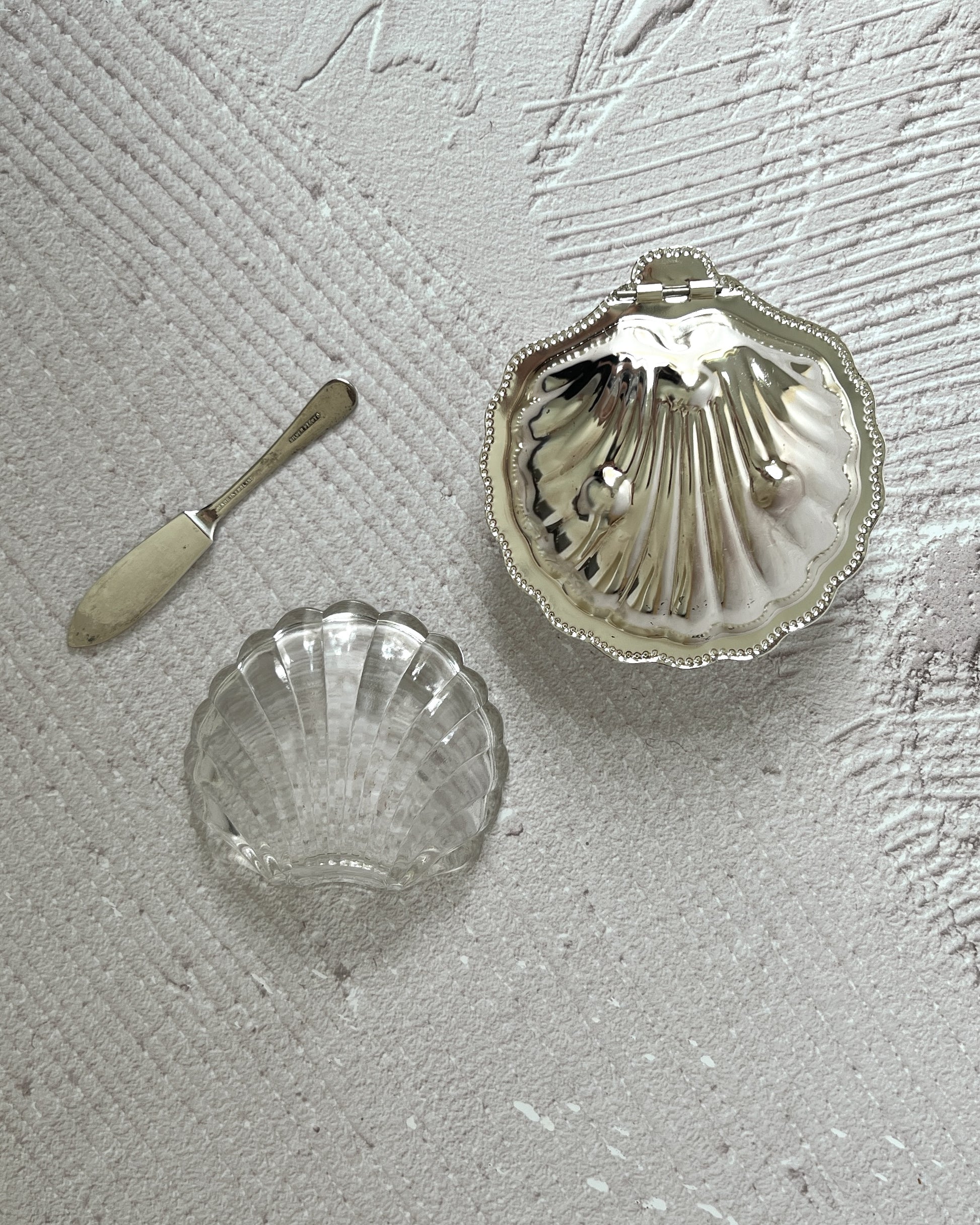 Elegant vintage Sheffield silver shell dish serving butter, demonstrating its versatile use as a sophisticated dining accent or coastal decor piece.