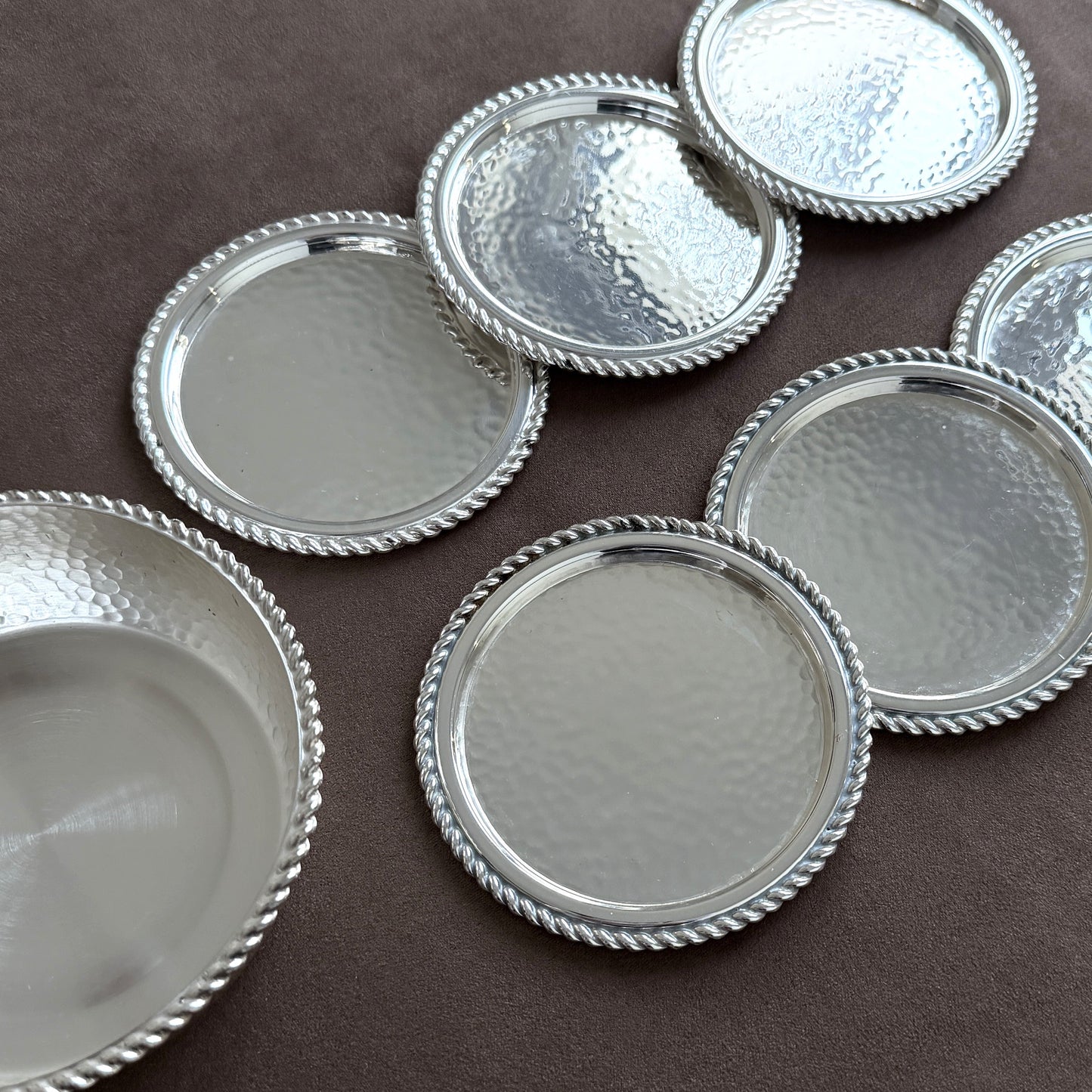 A high-walled vintage hammered silver wine bottle coaster designed to catch drips while adding mid-century luxury to a dining table or bar cart.