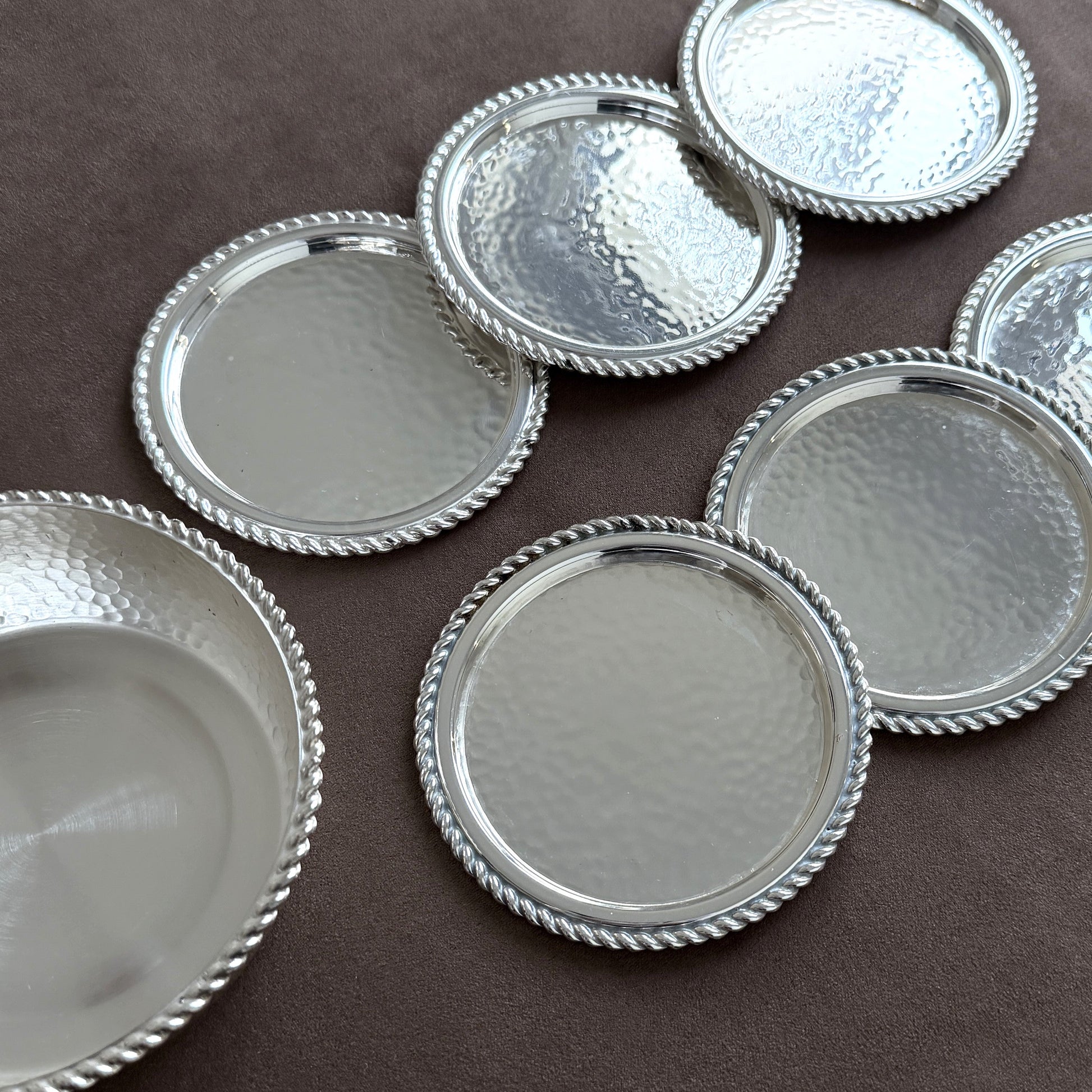 A high-walled vintage hammered silver wine bottle coaster designed to catch drips while adding mid-century luxury to a dining table or bar cart.