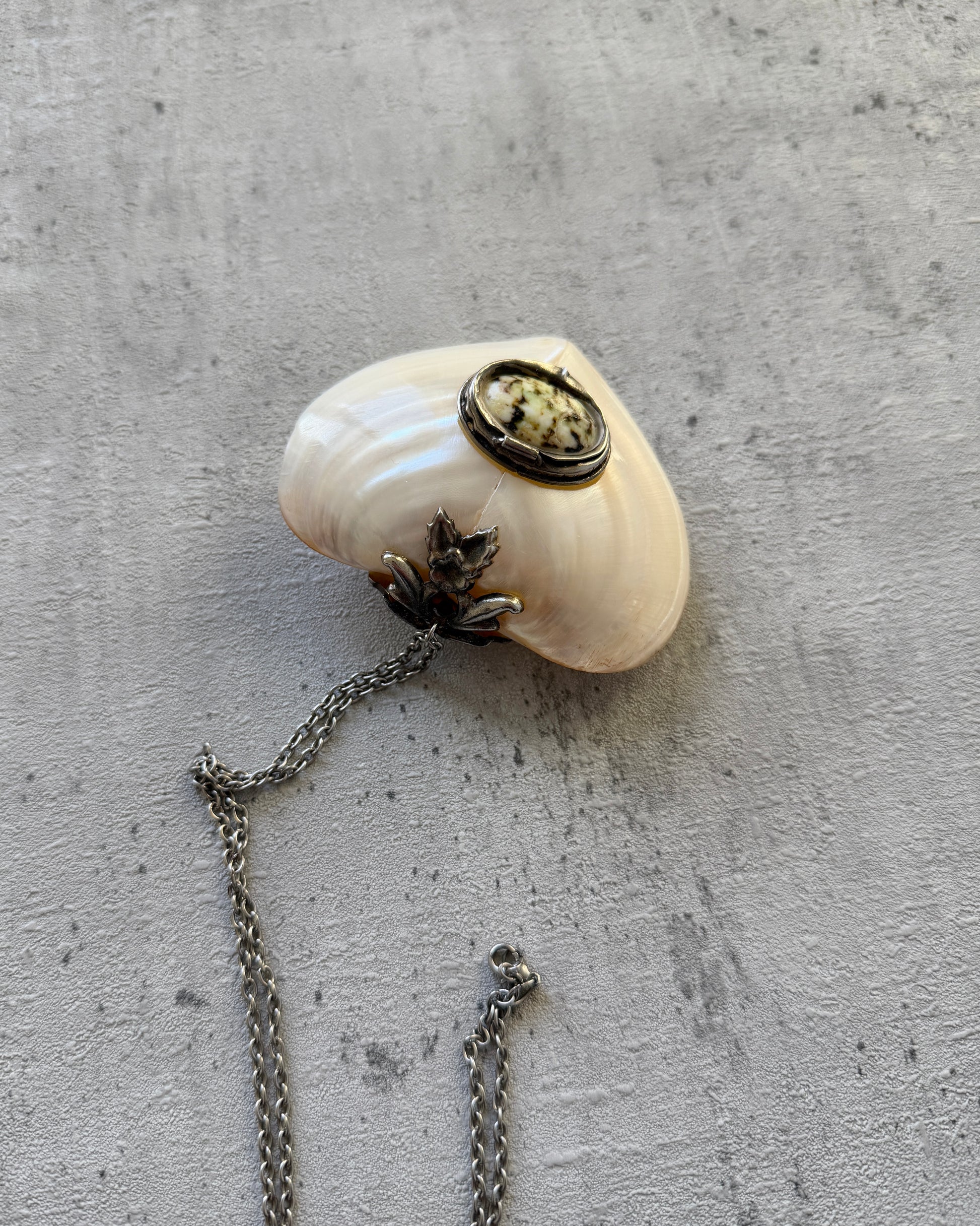 Close-up of the handmade mother-of-pearl heart box, highlighting the smooth, iridescent natural shell texture and vintage metal hardware.