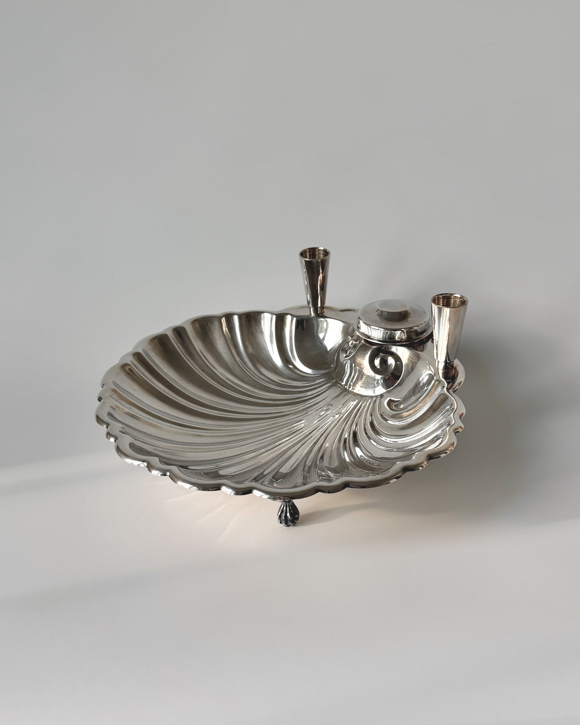 Side profile of the silver-plated shell dish showing the dual taper candle holders and elegant supporting feet for an elevated dining table display.
